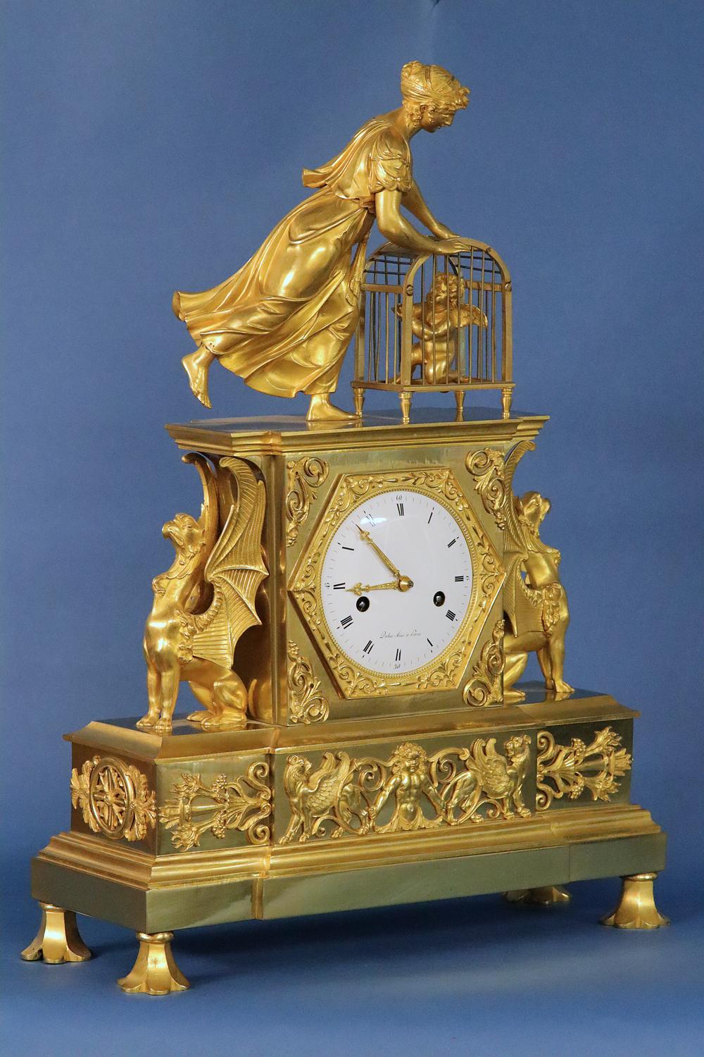 Maker: 
Dubuc Aine à Paris

Case: 
The well-cast and finished ormolu is surmounted by a female figure leaning over and opening the top door of cage containing a putti. Flanking the clock are two large winged griffins on a stepped base with