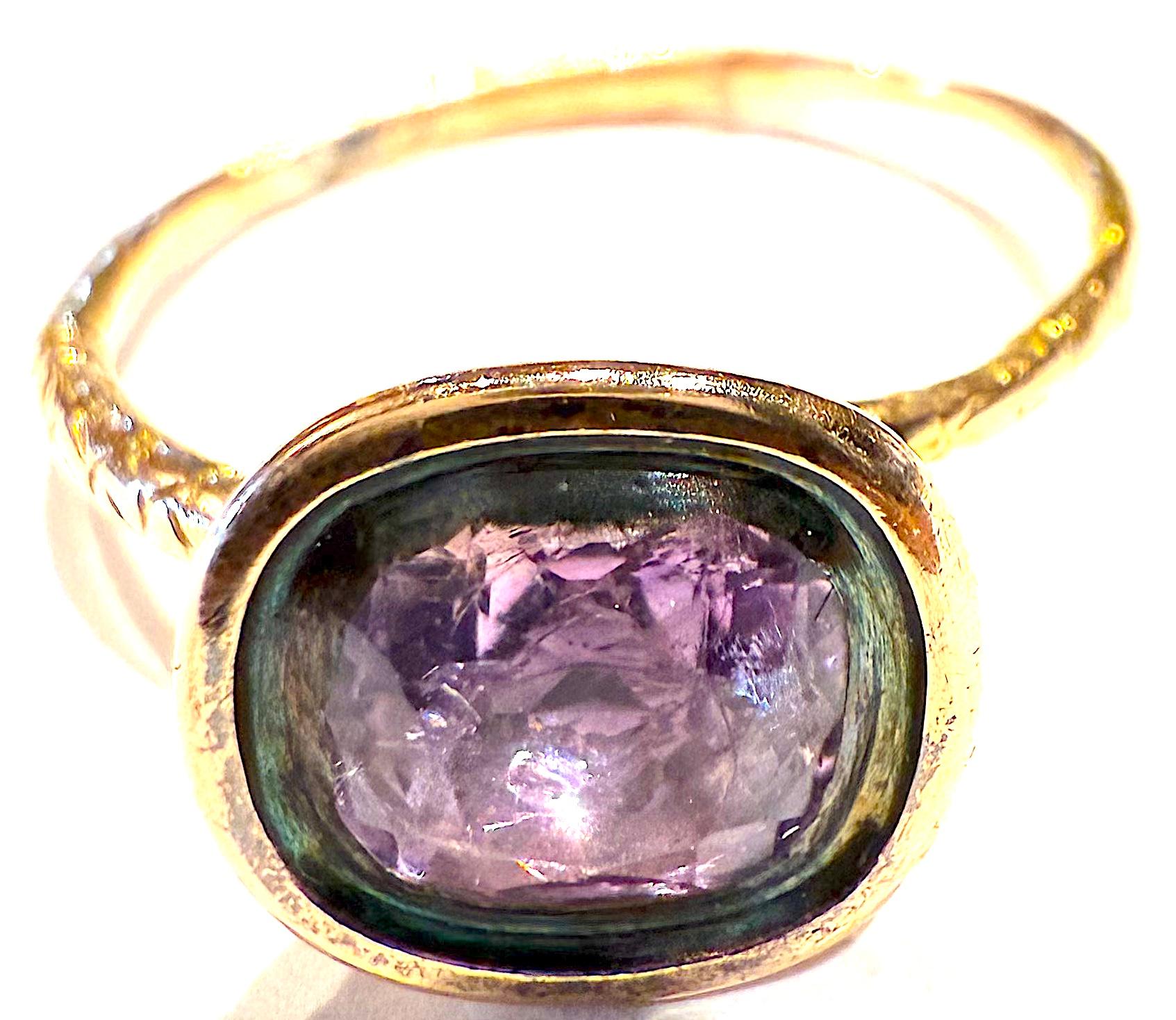 Il nostro affascinante anello d'epoca reggenza a 15 carati è composto da un'ametista sfaccettata in un'incastonatura a cesto del peso di circa 1,20 carati, incastonata in una fascia d'oro 15 carati a forma di ourobouros,  un serpente che si morde la