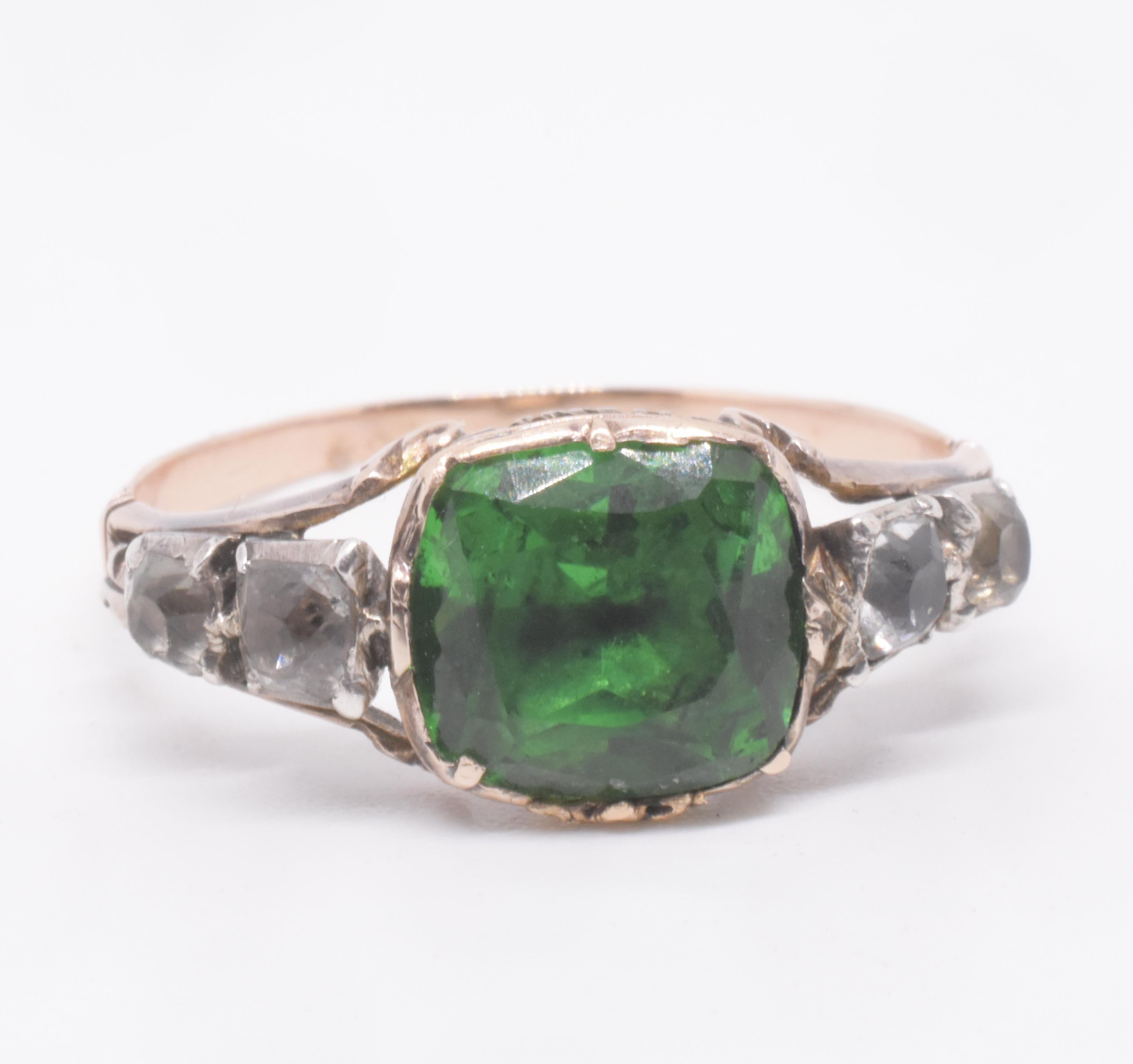 Anillo georgiano de pasta verde en engaste de cesta flanqueado por dos pastas claras a cada lado. La pasta es vidrio coloreado o transparente, a menudo plomo o sílex, tallado de la misma forma que las piedras preciosas y utilizado como sustituto de