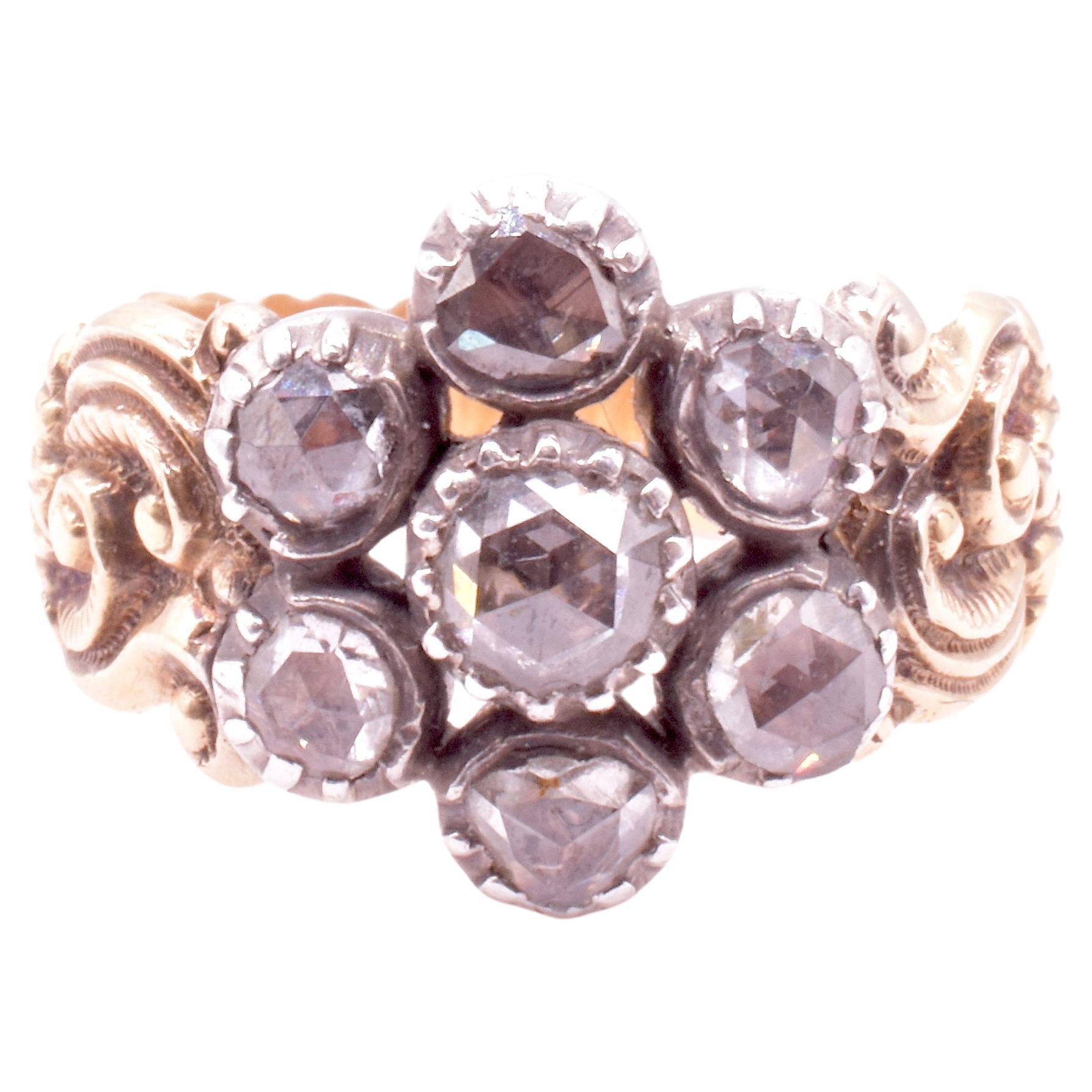 Early Georgian rose diamond cluster ring set in silver with an 18K gold embossed band. This is a gorgeous example of the work of a Georgian goldsmith. The ring is baroque in design, with the deeply and beautifully carved wide band a perfect foil to