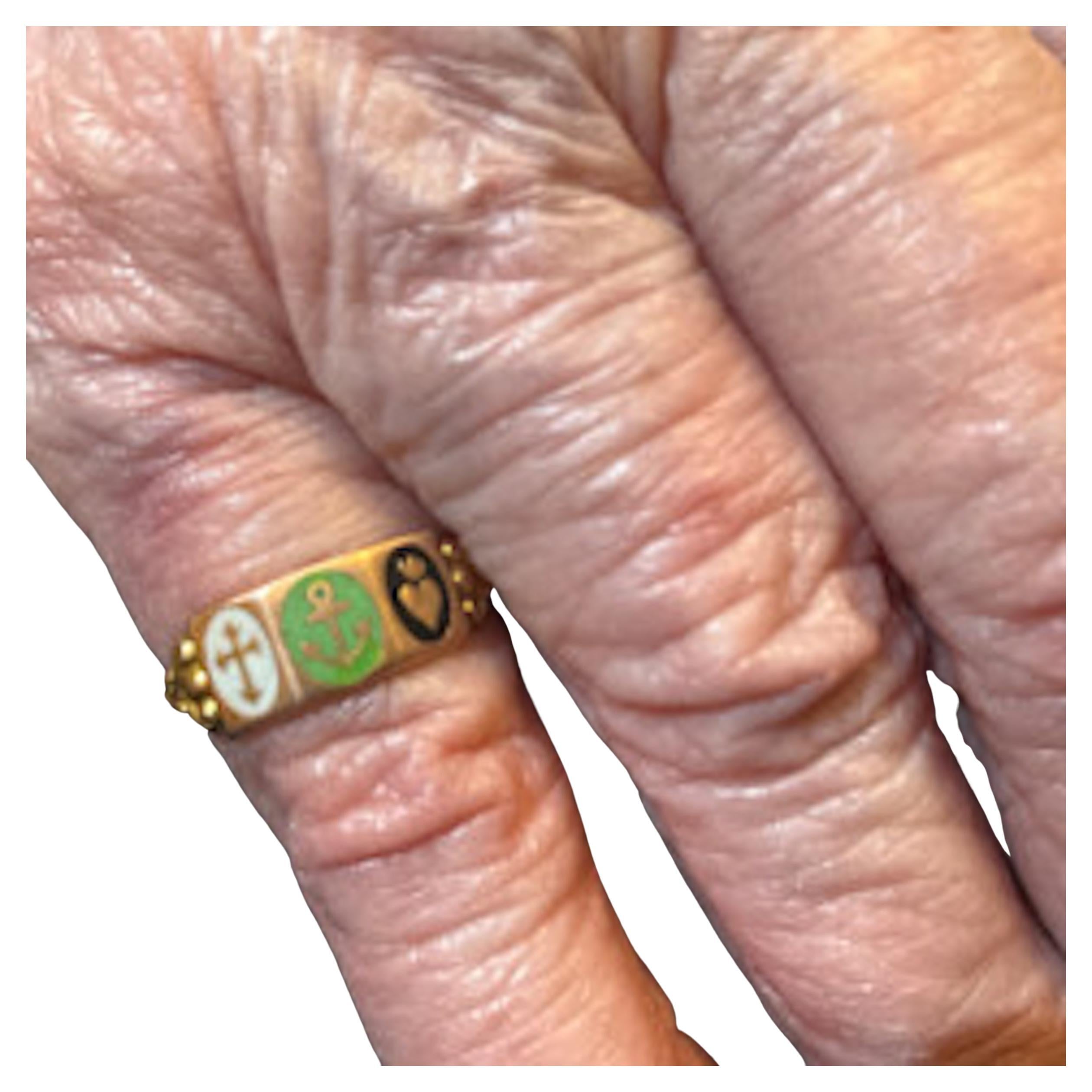 A sweet enamel ring of 18 karat gold, made late 19th century / early 20th century with a trilogy of a cross, an anchor and a heart,  depicting 