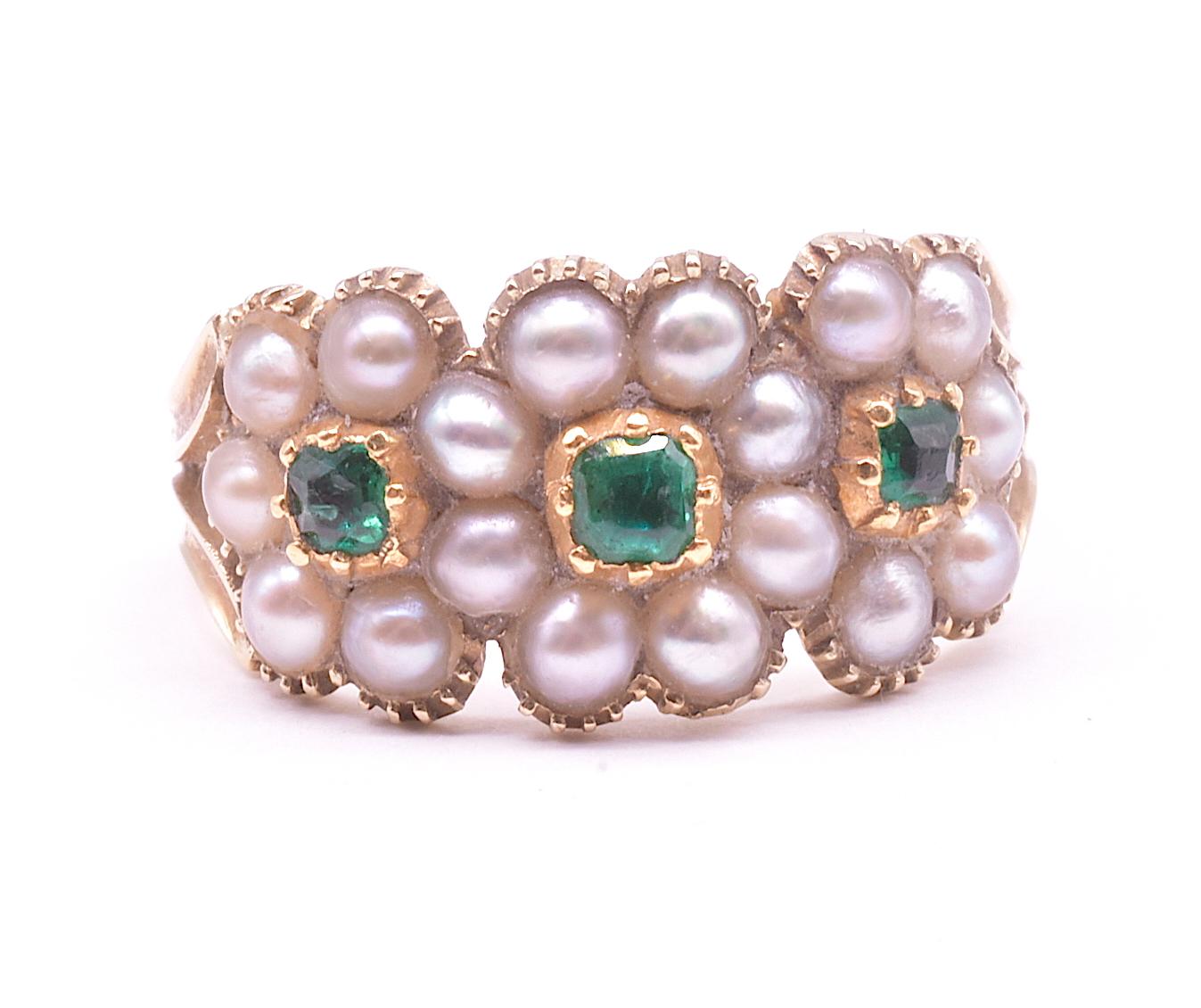 Wonderful early 19th century Gaorgian  ring that features three overlapping daisy clusters composed of seed pearls and flat cut emeralds set with a closed gold back.  The stones are set in classic Georgian crimped settings. The interesting carved