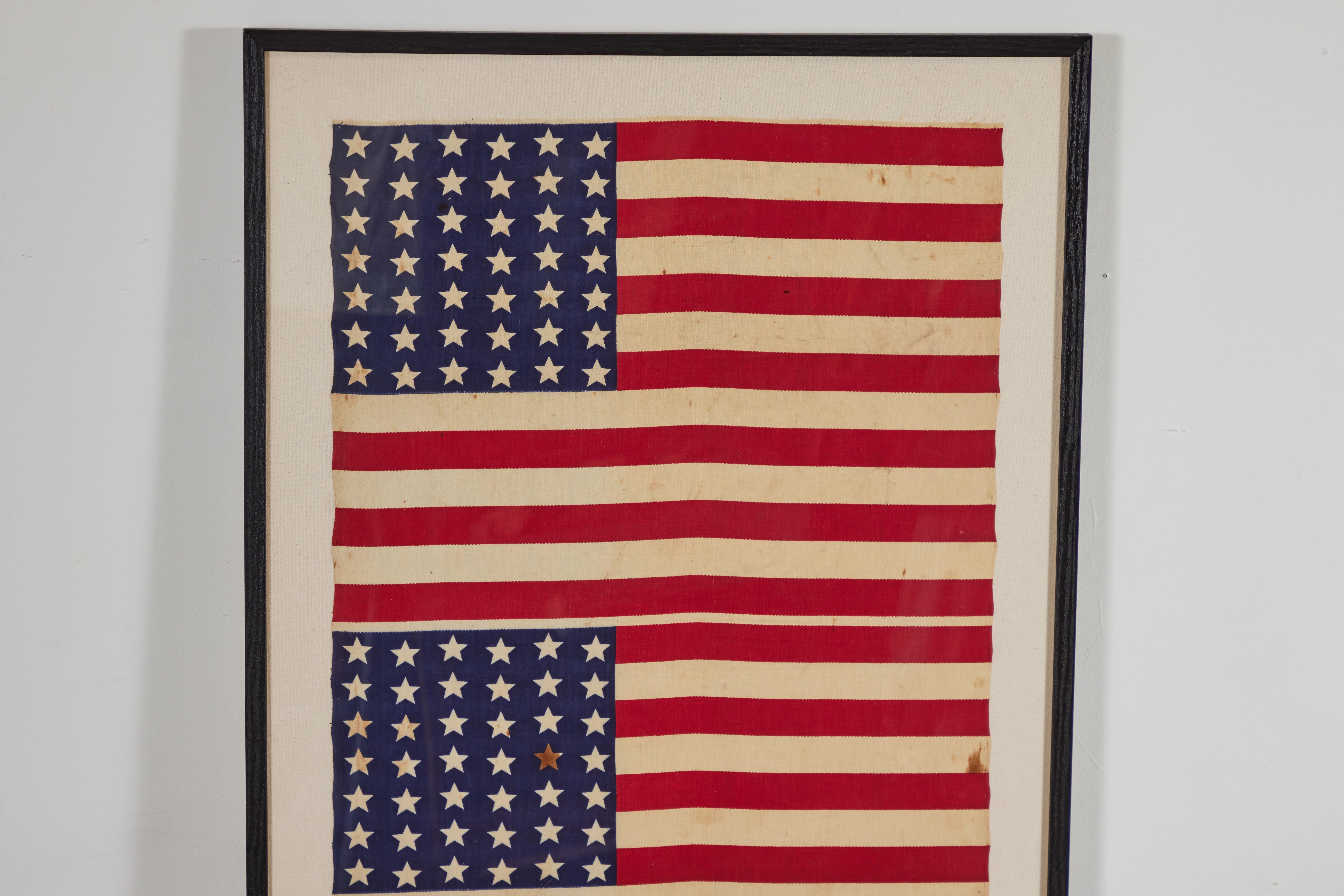 Framed uncut roll of 42 star American Flags. Washington state was the 42nd state to enter the union. This flag was never official as four other states entered the union that same year. Graphic linear star pattern.
 