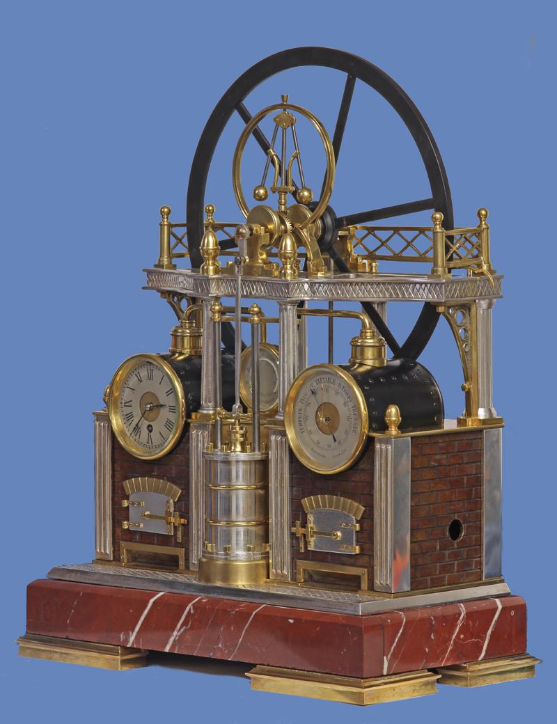 Case: 
The patinated, gilt and silvered-bronze and marble case depicts a late-19th century steam engine. It has a patinated brick work furnace with decorative doors and reeded pilasters to the corners. Standing on fluted columns is a second level