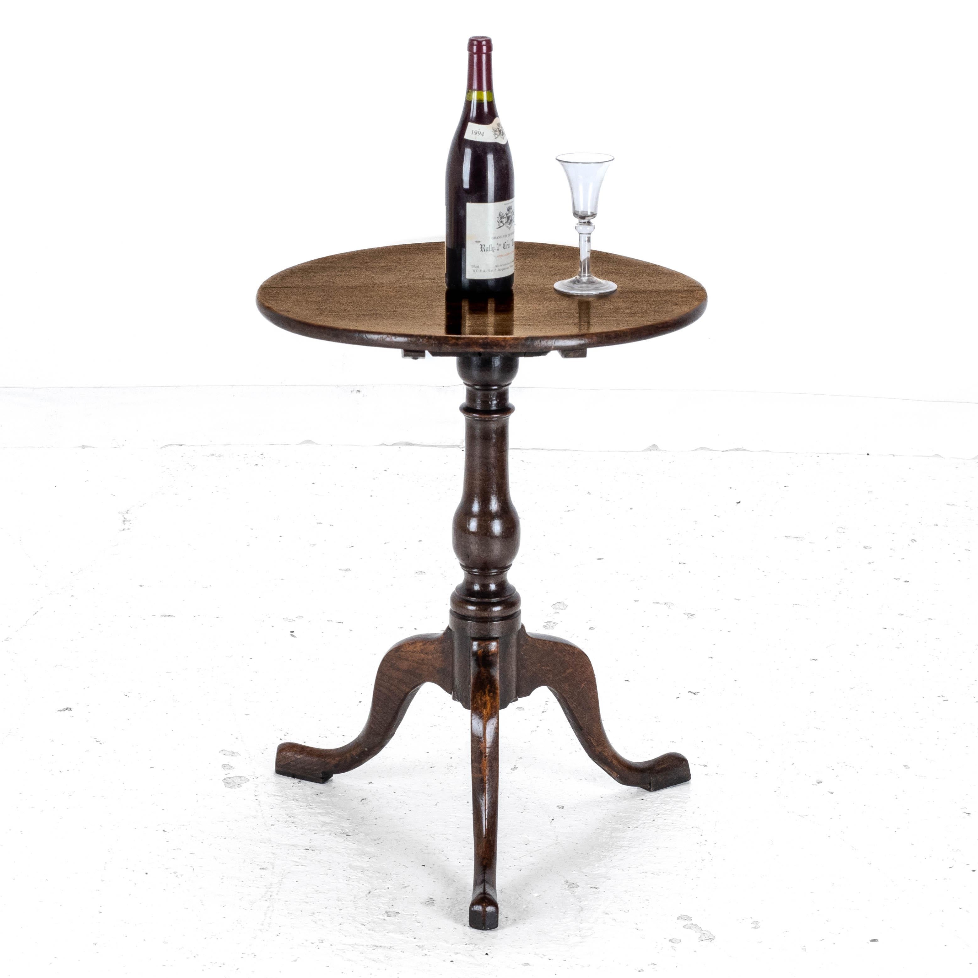 A George III period, oak tripod wine table, dating from the late c.18th. This charming table, features an circular shaped solid oak plank top. Tilt-top hinged mechanism. Supported by a turned baluster stem, raised on a tripod of cabriole type