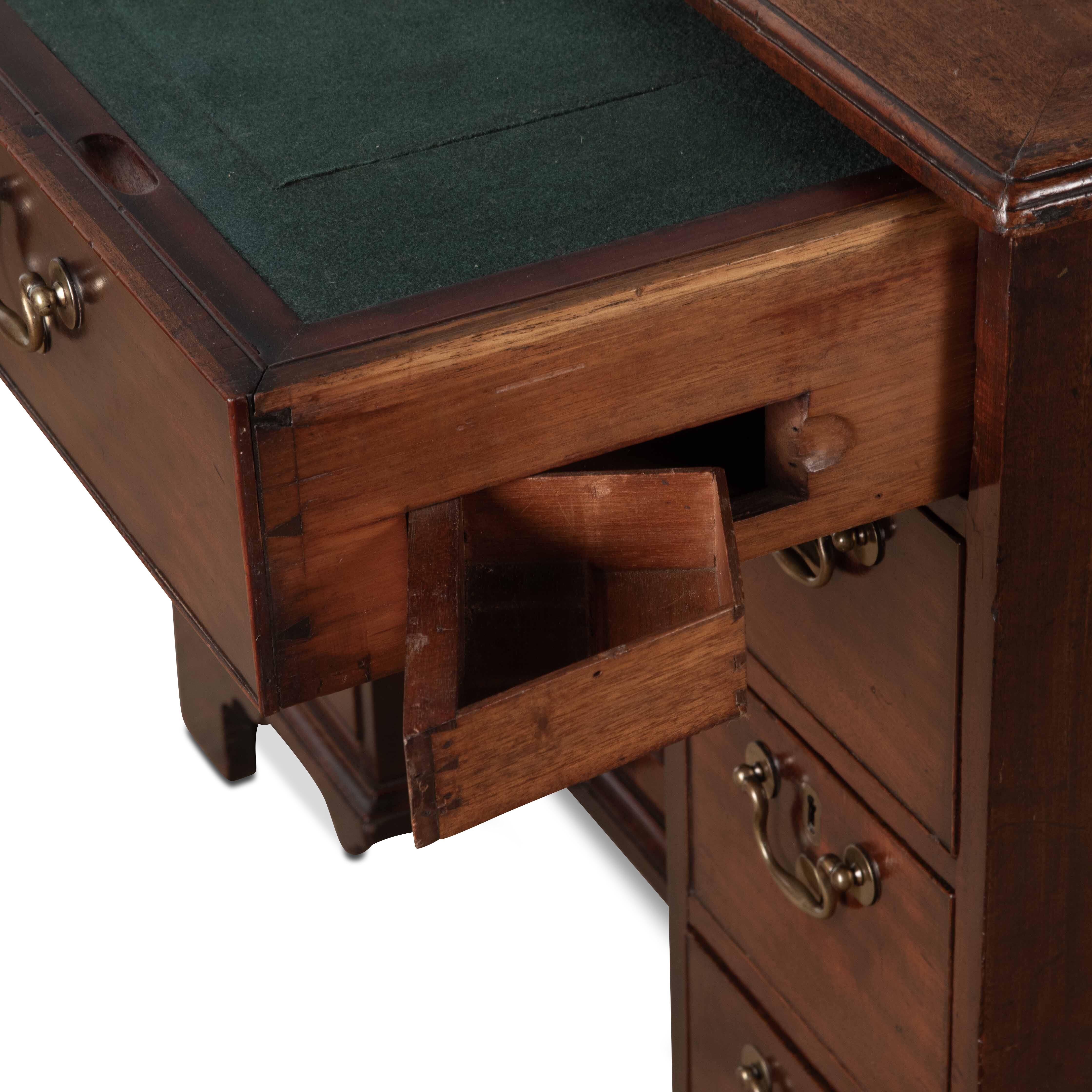  A well made early Geo III mahogany kneehole desk in the manner of Giles Grendy, of unusual form and features. Slightly oversized it holds a presence of quality craftsmanship, with cleated ends to the top with moulded edges, above a long fitted