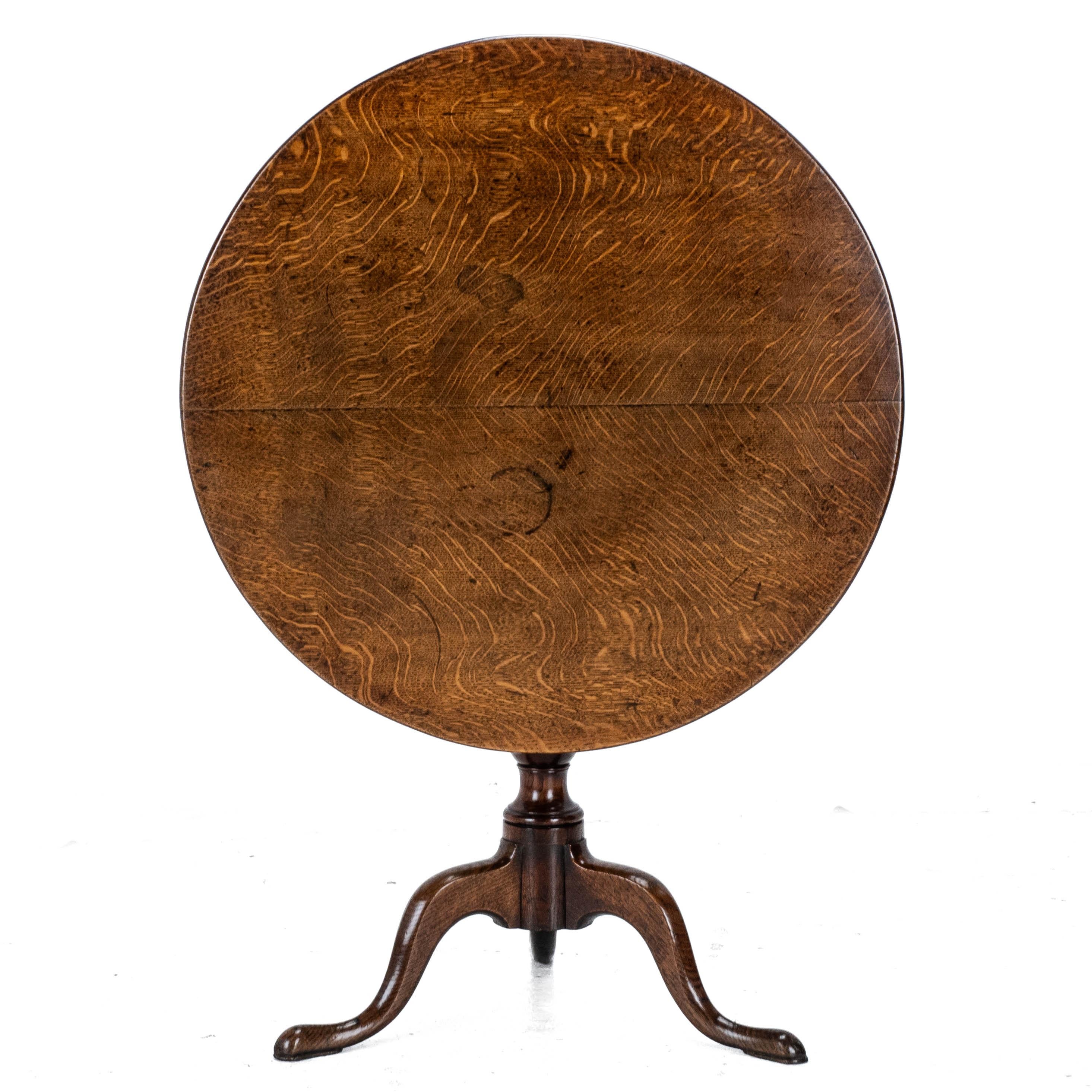 A George III period, oak tilt-top tripod supper table, dating from the second half of the c.18th. This stunning, high quality country table, features a very well figured, book matched quarter sawn oak top. Supported by a turned baluster stem, raised