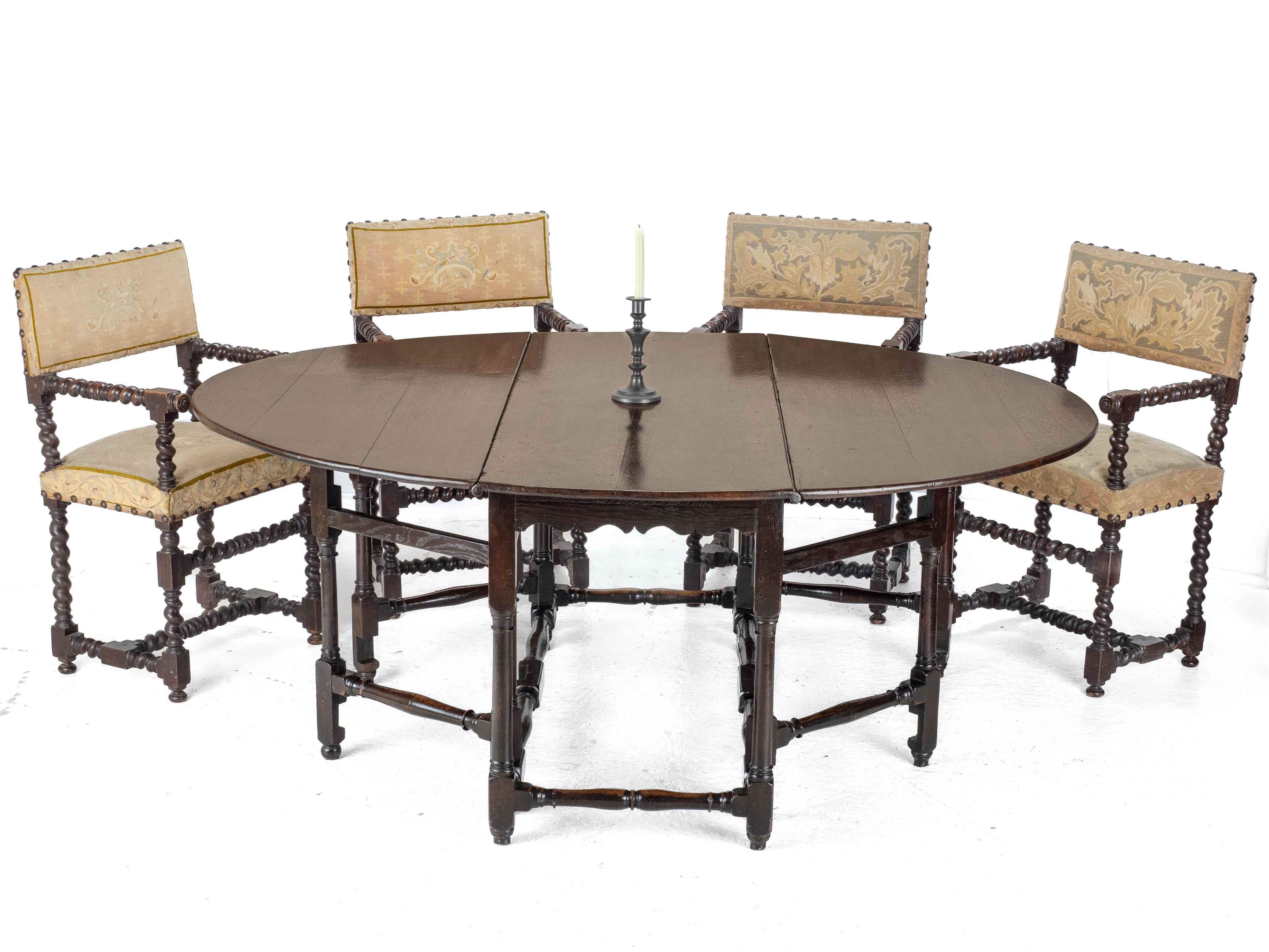 A set of 4 Cromwellian style, walnut framed, barley twist carver armchairs, dating from the 18th century. This set of chairs features upholstered back pads, covered in needlepoint tapestry covers and matching seats. There are two designs, each on