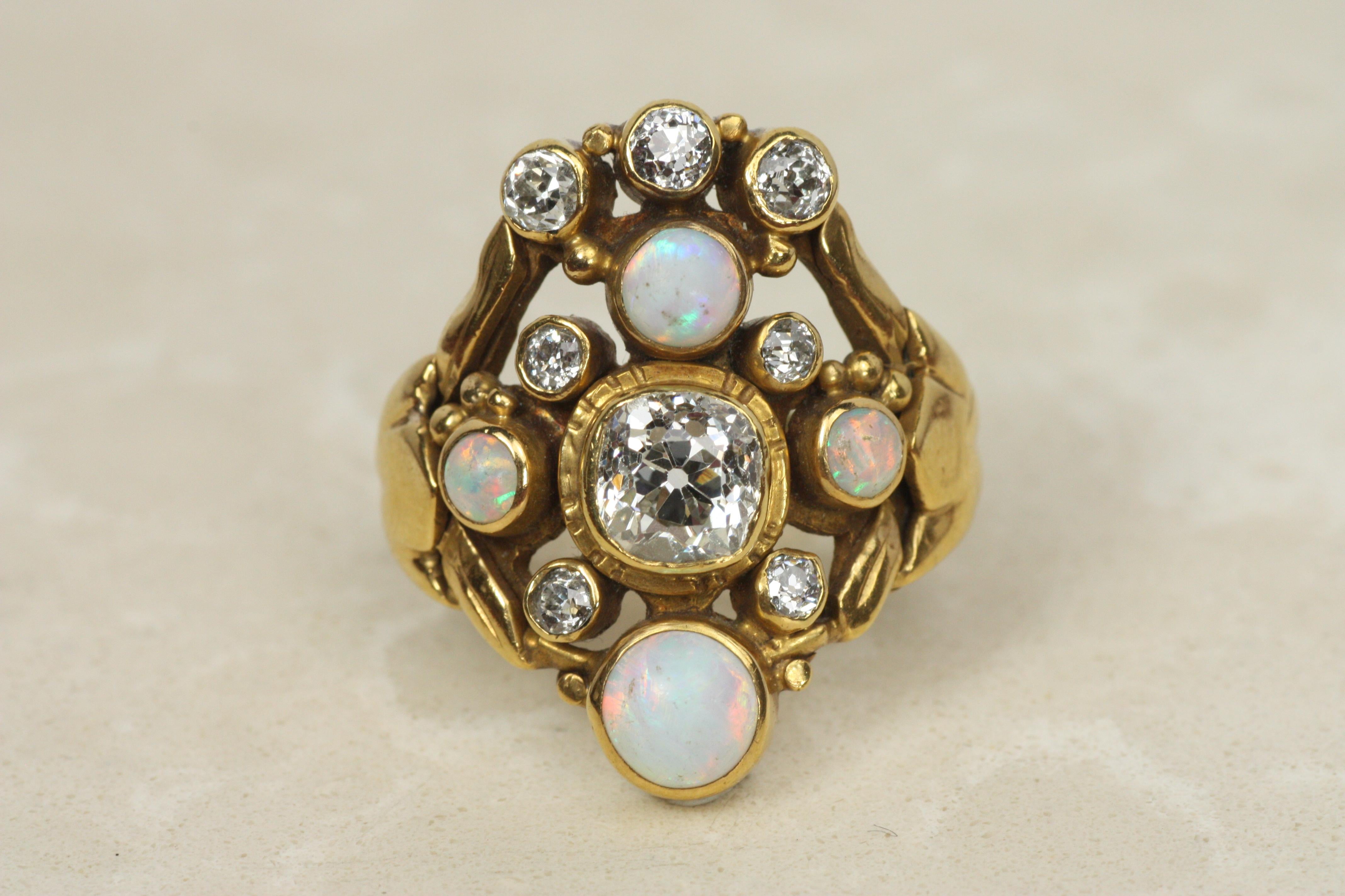 This extraordinary Art Nouveau ring circa 1900 captures the ethereal beauty of its era with a harmonious blend of old mine cut diamonds and glowing opals. At the center sits a stunning 0.80ct diamond (VS2, E-F), surrounded by seven accent diamonds