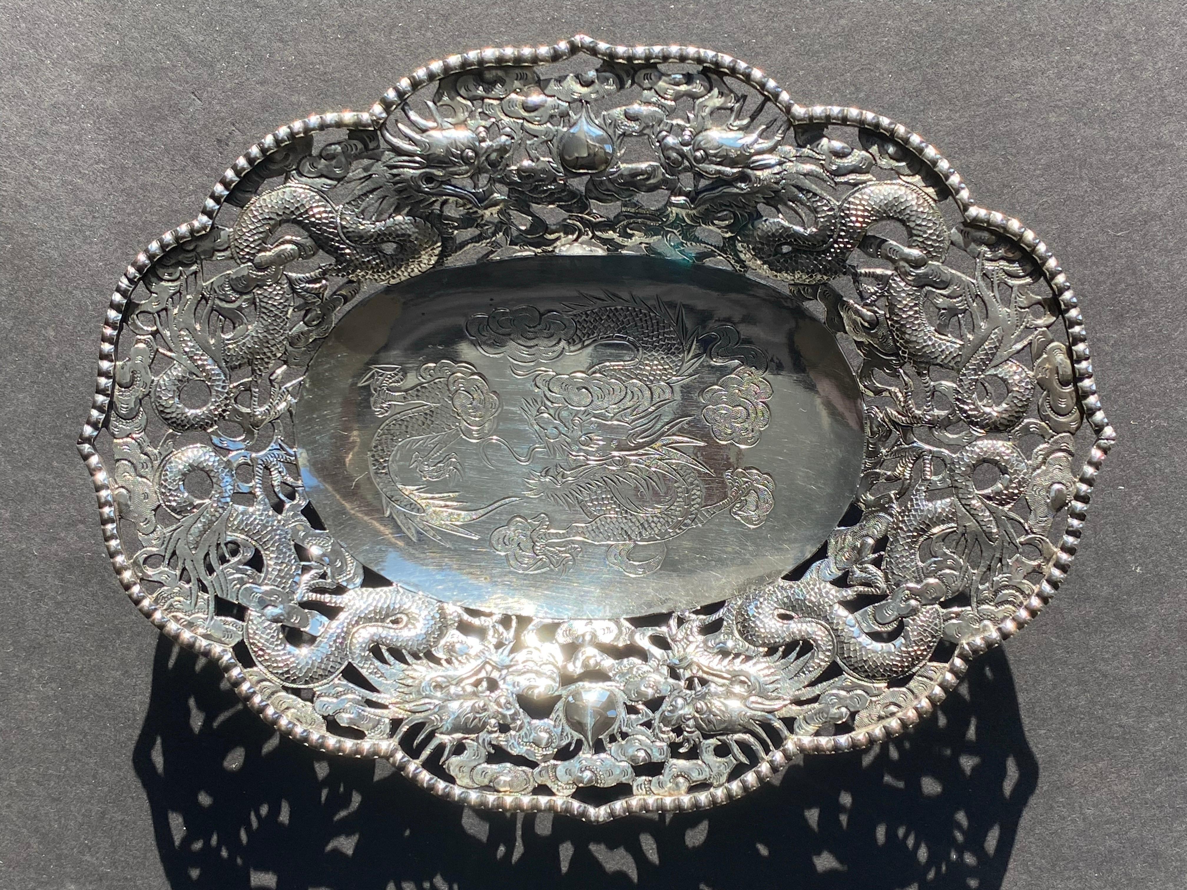 Cuenco de dragón poco profundo de exportación chino de plata al 90%, c. 1900, de Wang Hing. El cuenco reticulado está fundido a la exportación, tallado, grabado a martillo y cincelado en toda su superficie. El cuenco presenta un motivo central de un