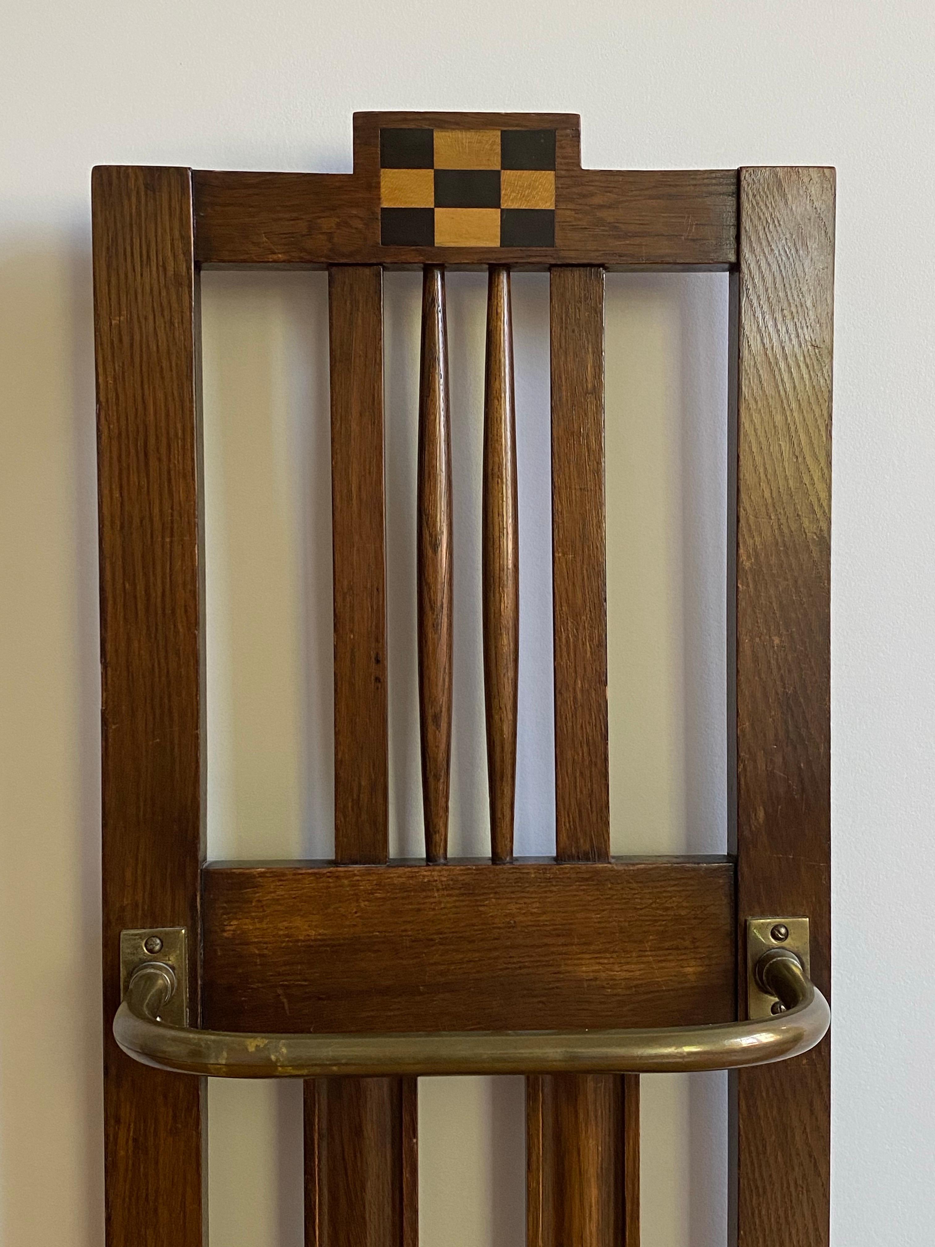 Ein um 1900 entstandener englischer Schirm- oder Stockständer aus Eiche, Mischholz und Messing mit geometrischer Schachbrettintarsie. Die vertikalen Pfosten sind sowohl gedreht als auch geradlinig und verleihen dem Stand eine architektonische