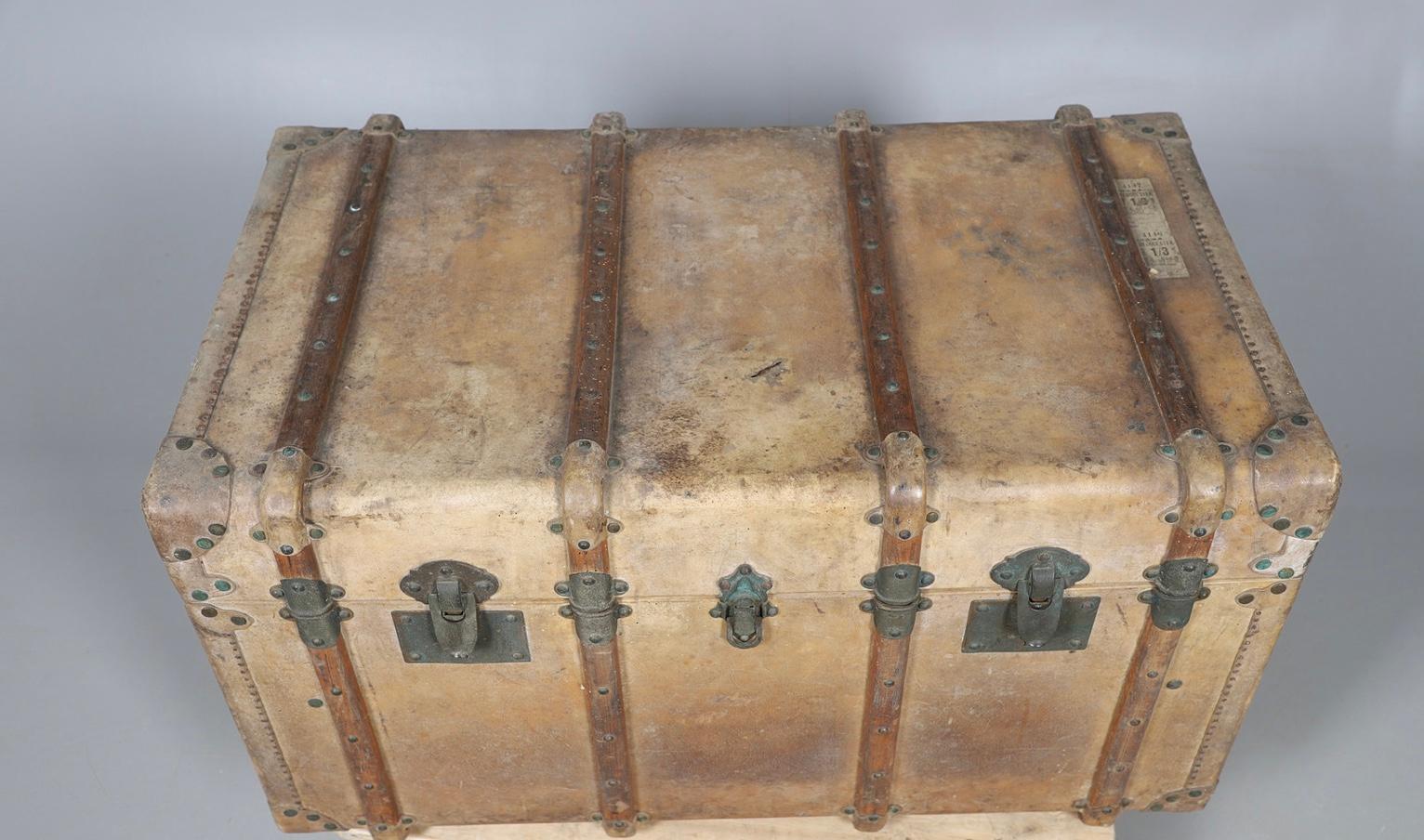 Questo bel baule in pelle dei primi anni del Novecento, di colore marrone chiaro/vellum, è dotato di maniglie in pelle per ogni lato.
Forse una scuola  Il tronco presenta le iniziali del proprietario, EC, e sono ancora visibili alcune etichette da