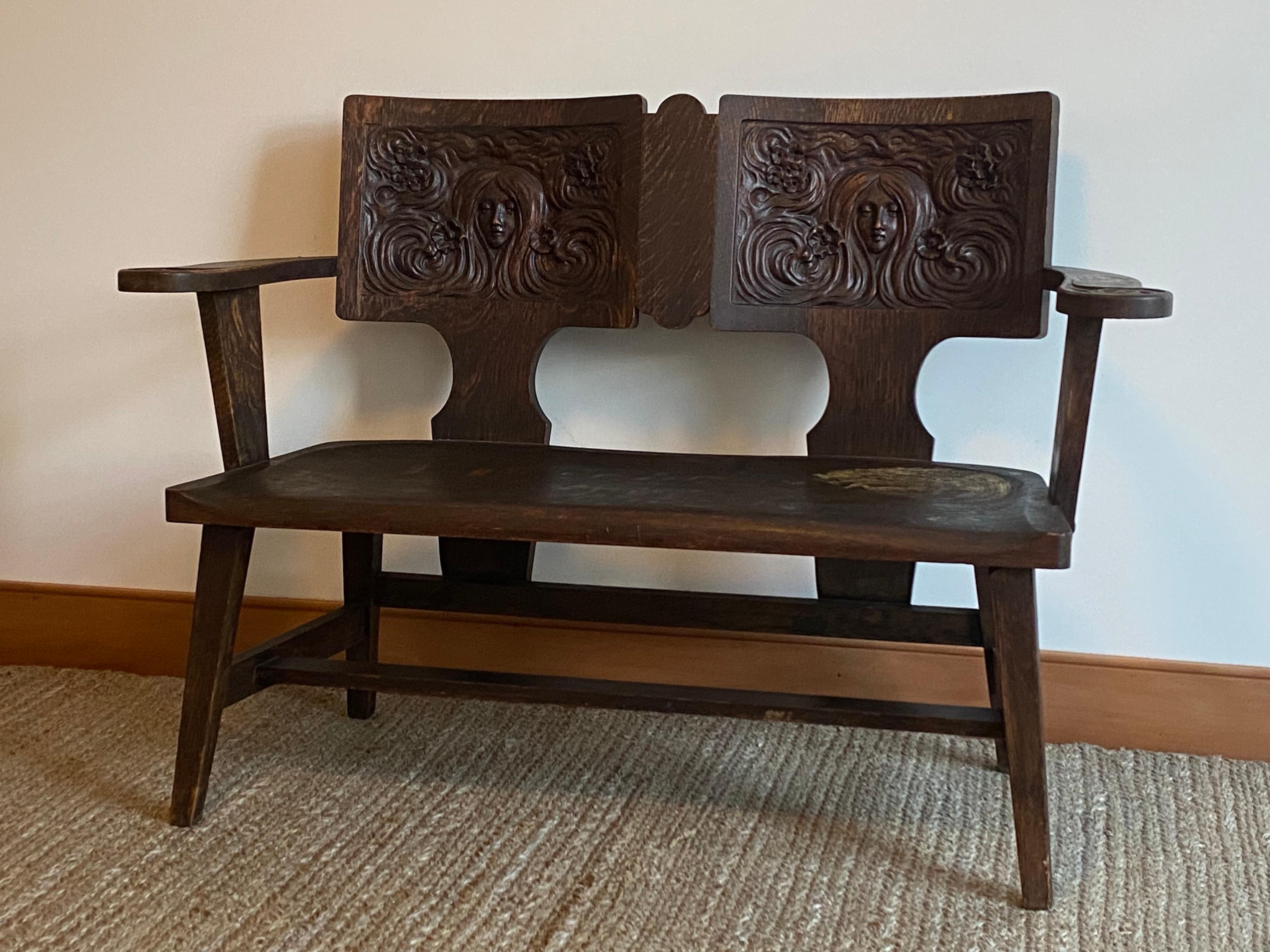 A rare, carved oak Symbolist bench by the George Arndt Chair Company. Art Nouveau design in American furniture is exceedingly rare and this bench exhibits the best design elements of the period. The carved faces on the back rests recall the artwork