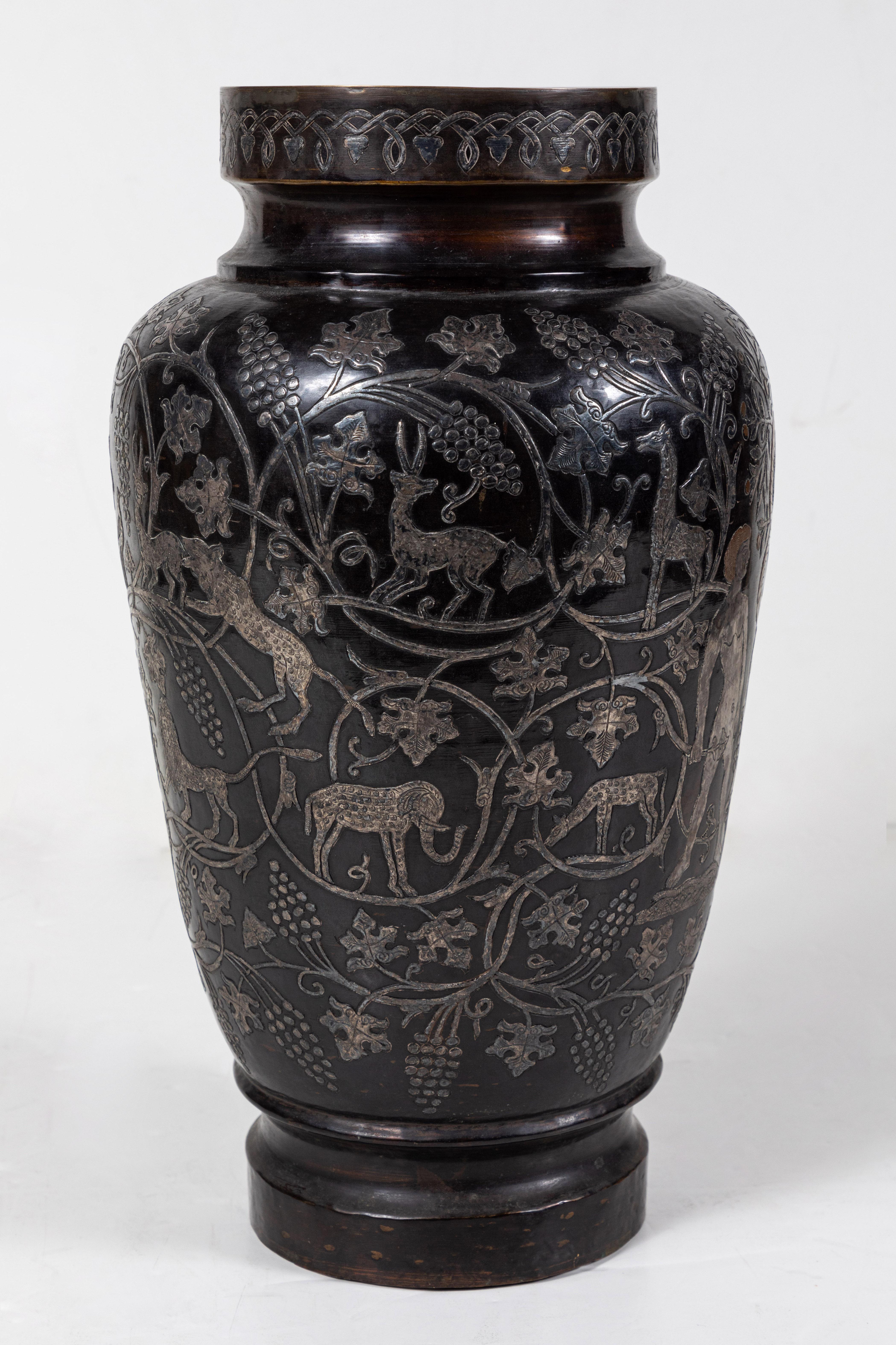 Striking, richly detailed, chased metal vase showing scenes from the Garden of Eden, including the Tree of Life surrounded by a coiled serpent. The whole surrounded by scrolling, fecund grape vines with a variety of animals. 