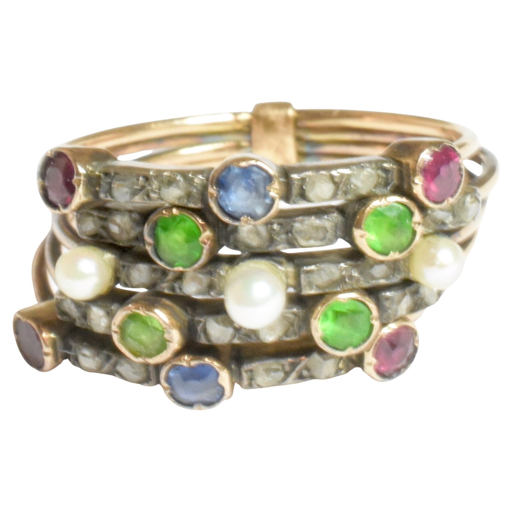 Questo anello harem edoardiano in oro 14k contiene una serie di diamanti taglio cuscino, perle, zaffiri, rubini e granati demantoidi verdi. I granati demantoidi sono stati estratti in Russia e sono molto apprezzati per il loro colore verde mela. 