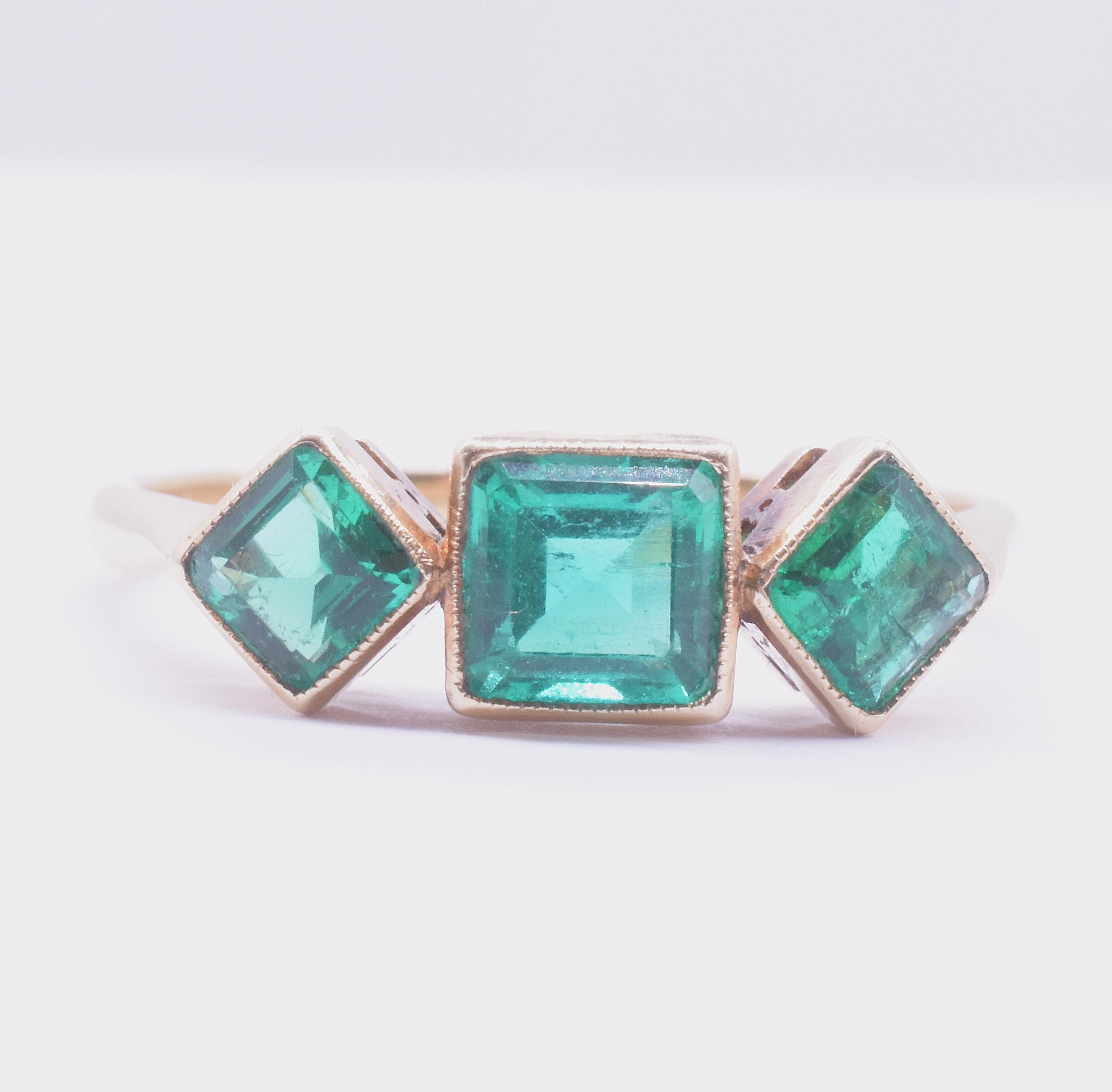 Dieser frühe Art-Deco-Ring mit 3 Steinen und 18 Karat Smaragdschliff rühmt sich mit 3 kolumbianischen Smaragden von 1,2 Karat im quadratischen Smaragdschliff. Die Smaragde haben ein kantiges, modernes, geometrisches Design, bei dem die flankierenden