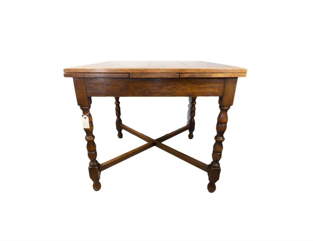 Circa 1900 draw-leaf table from England made from Tiger Oak. The top is paneled, and has two leaves that pull out to extend the length of the table to 57 inches. The leaves are paneled as well. The apron is simple and is supported on hand