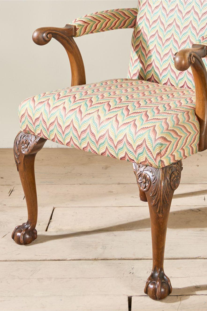 This is a lovely quality English country house open armed desk chair. The carved legs and shaped arms give this a real elegance and shows the chairs quality. It is currently upholstered in an attractive fabric. This wasn't done by use but is clean
