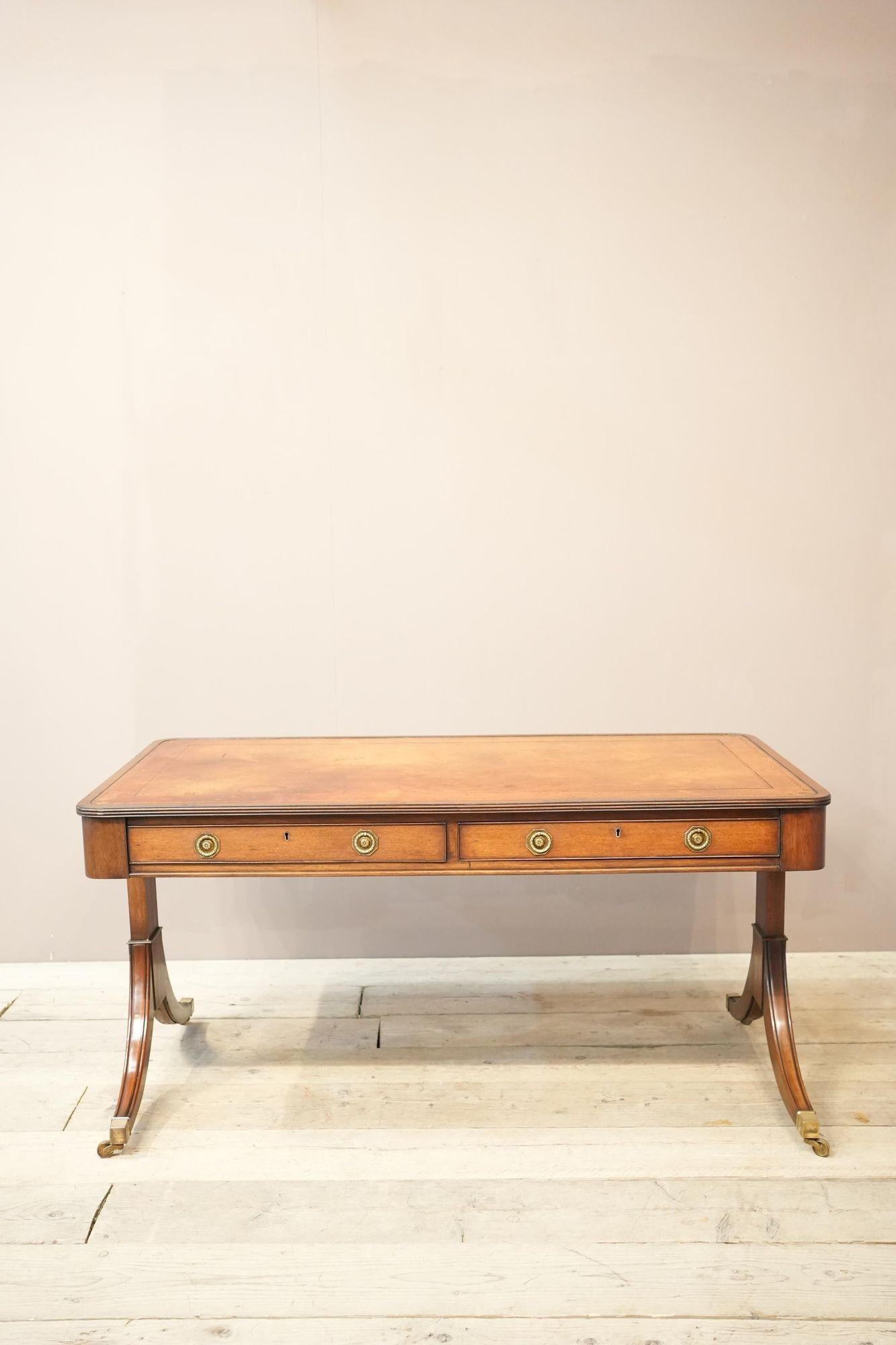 This is a very impressive large size Georgian style desk. It has an immaculate mahogany body with elegant details and capped with brass casters. On top it has an amazing tan leather patinated leather (less orange in real life). The whole piece has