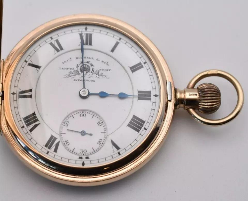 This circa 1930 half hunter pocket watch is a remarkable piece crafted by the esteemed Thos Russell & Son of Liverpool, renowned for their precision and quality timepieces. Encased in 9ct gold, the watch exemplifies the elegance and sophistication