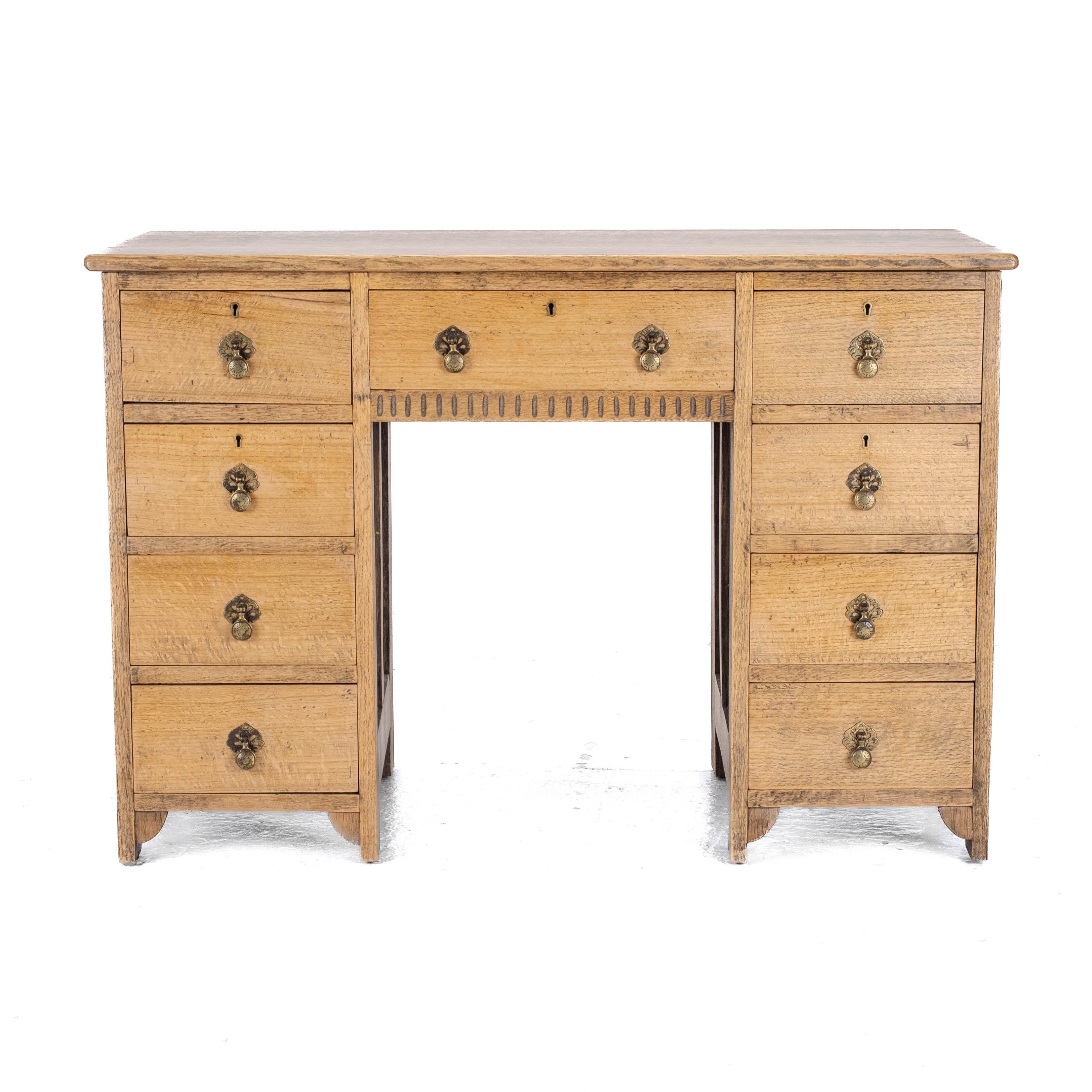 A golden oak desk in the Art and Crafts taste dating from 1920's or 30's. Solid oak throughout with attractive figuring. Oblong shaped plain top. Two banks of four drawers flanking a kneehole under a single drawers. All drawers with original brass