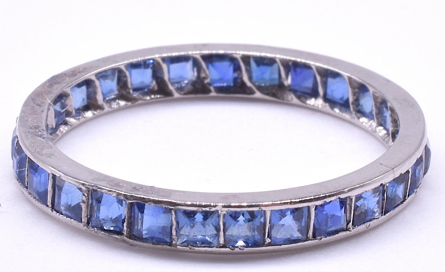 This classic Deco sapphire French cut eternity band is crafted in platinum and features 26 clear blue sapphires with a total carat weight of 1.15 carats. The band measures a US/Can. 7 ½ and is NOT size-able. It measures just over 1/16 inches