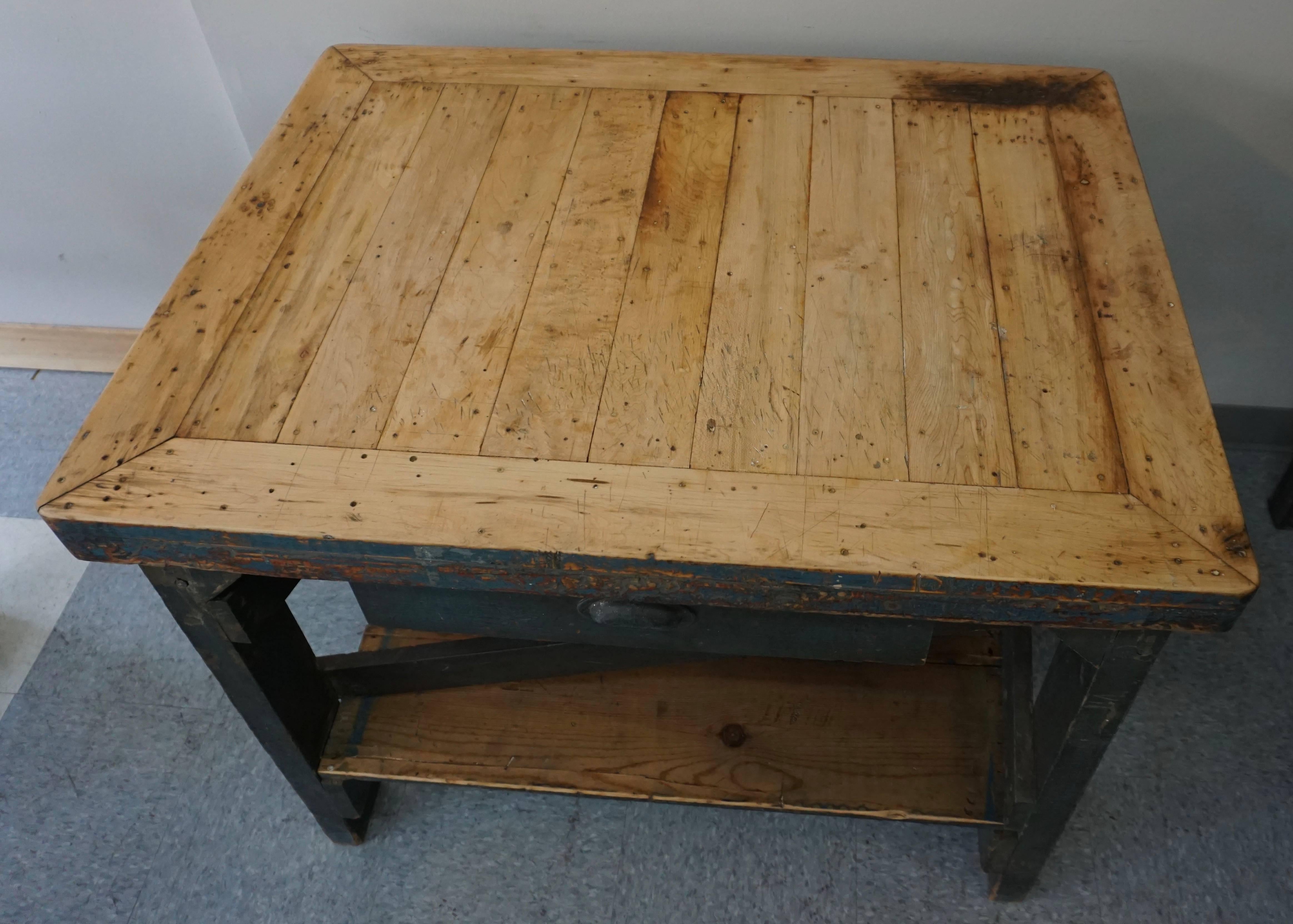 The top are solid maple boards that have wear and age appropriate for the vintage. The base has unusual supports and one drawer. Would make a great kitchen island. The base has original dark blue paint.