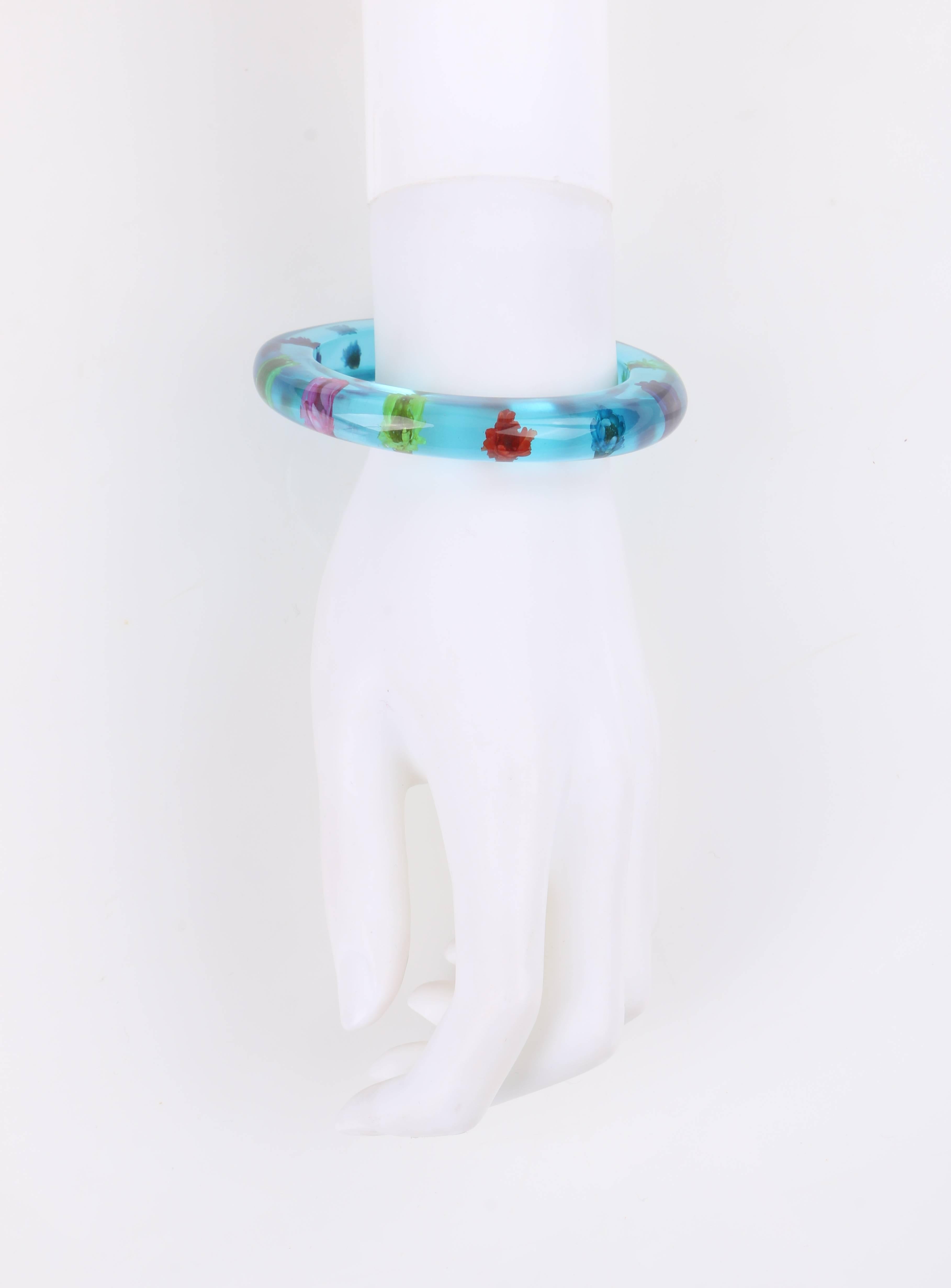 Vintage c.1940's teal blue translucent lucite multi-color flower embedded bangle bracelet. Twelve dried flowers in shades of pink, lime, yellow, red, teal, and blue embedded in teal blue translucent lucite. Circular shape. Slip-on style. Piece is