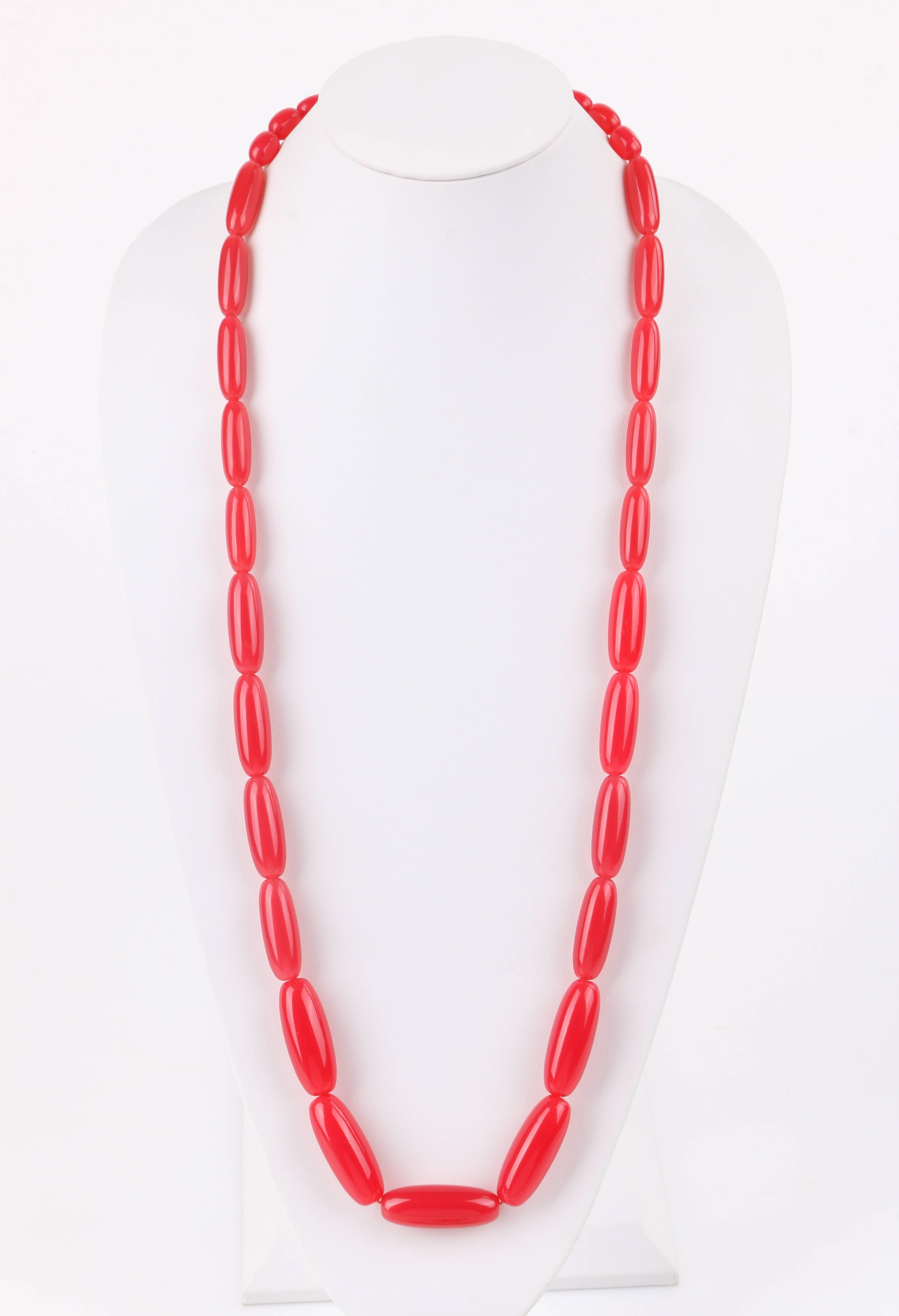 Vintage c.1940's watermelon pink oblong beaded long lucite necklace. Single long beaded strand made up of multiple oblong shaped lucite beads ascending in size (14 mm - 40 mm). Necklace has no fastener as it is a slip-on style. Piece is unmarked.