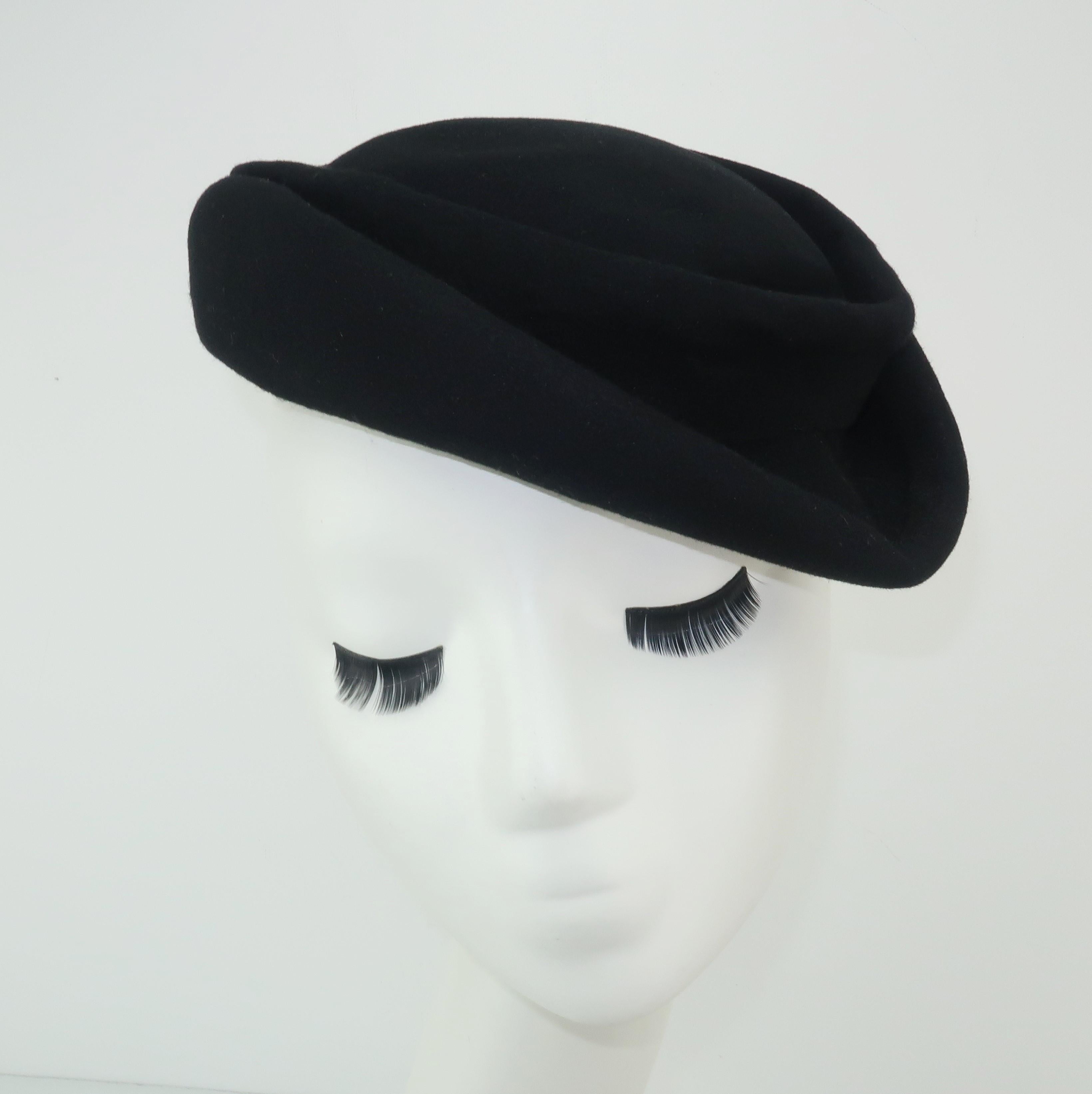 This C.1950 I. Magnin black wool felt tilt hat is fashioned with effortless folds and a jaunty silhouette perfect for adding a classic vintage look to a modern ensemble.  Take inspiration from a current Gucci hat, as shown in photograph 9, and add