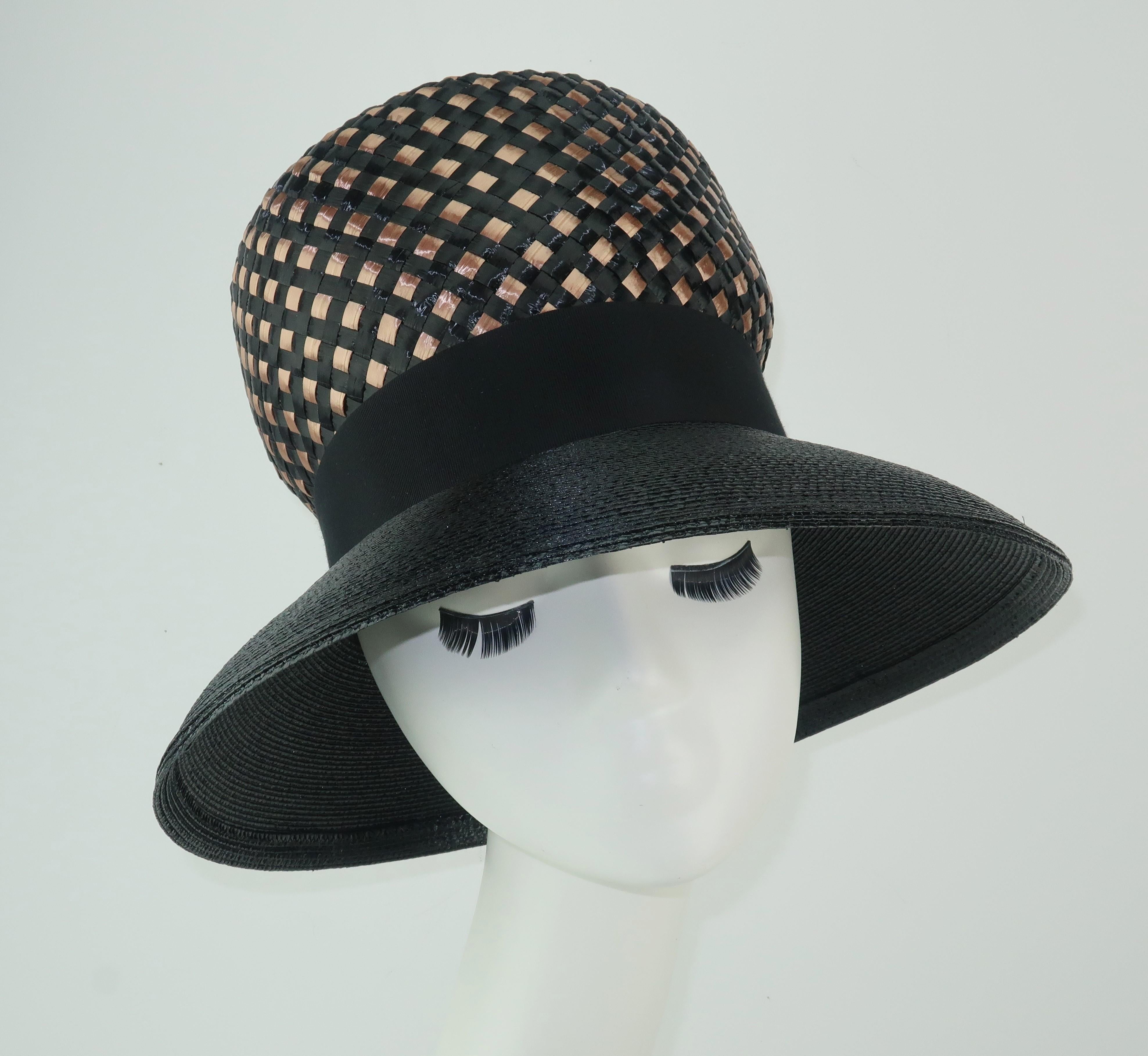 This Gwenn Pennington design is a 1960's example of throwing shade.  The fabulous silhouette with a sloping brim and exaggerated crown was a high style take on mod fashion.  Fabricated with a raffia weave, quality straw and a grosgrain ribbon accent