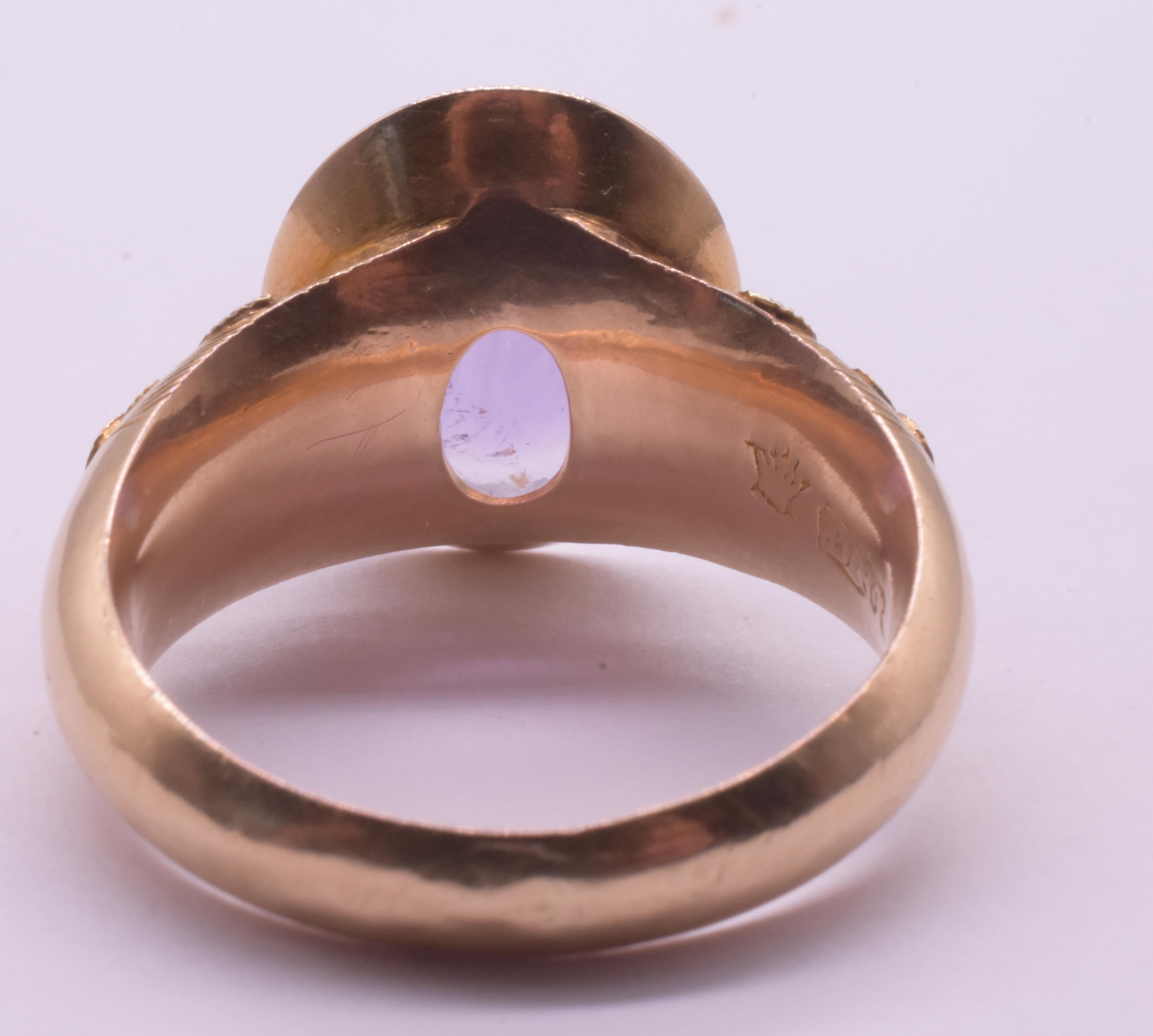 Wonderful mid-century signet ring with large 6 carat Amethyst stone at center and elevated, nicely textured carved shoulders with a romantic turquoise at the center surrounded by delicately curved petals. The ring is stamped with an 18K hallmark