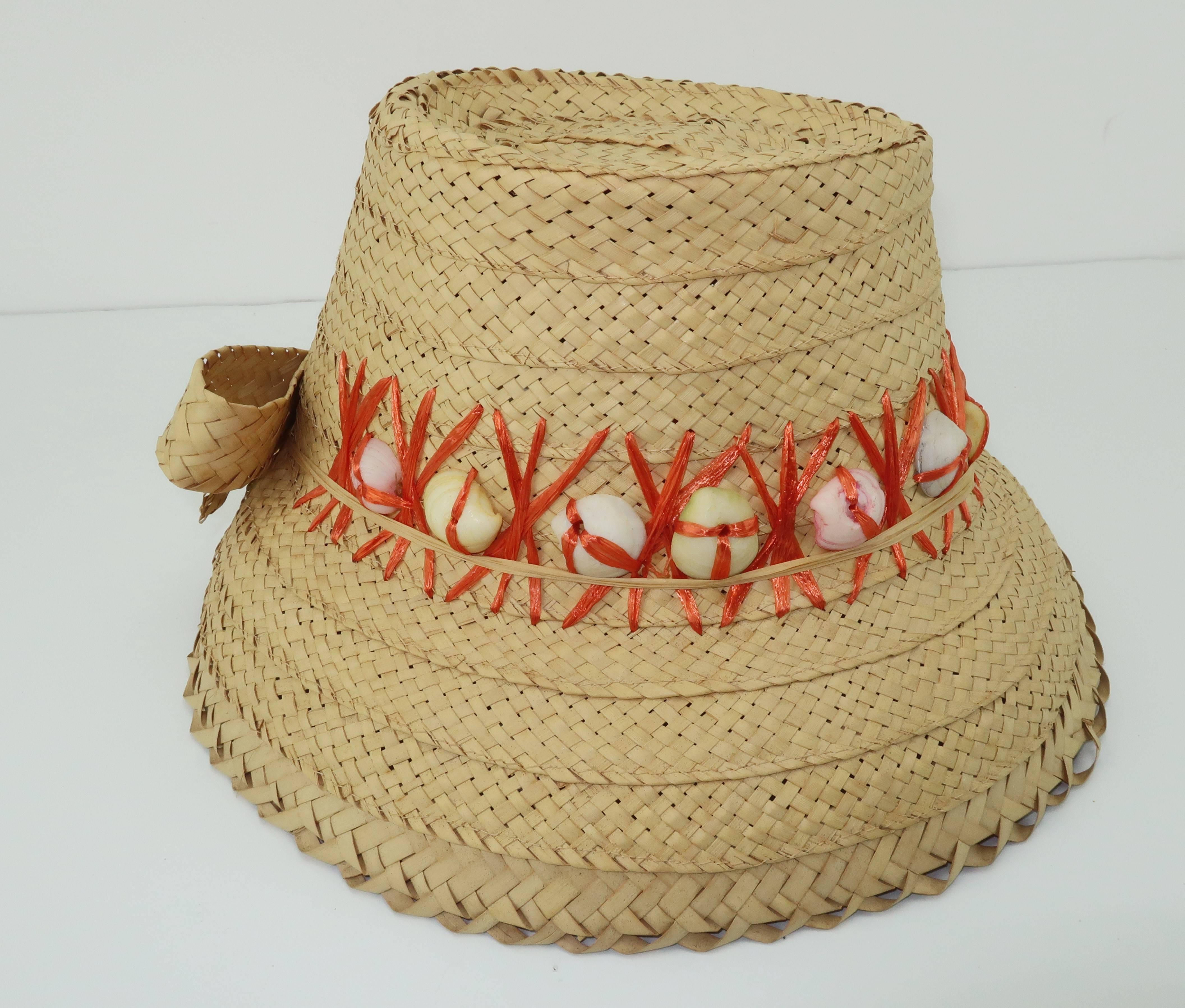 Make this C.1960 straw bucket hat your favorite beach companion for sunshine filled days.  The comfortable design is accented with orange raffia trim embellished with a bow and real sea shells for an authentic beachy look.  Very good condition. 