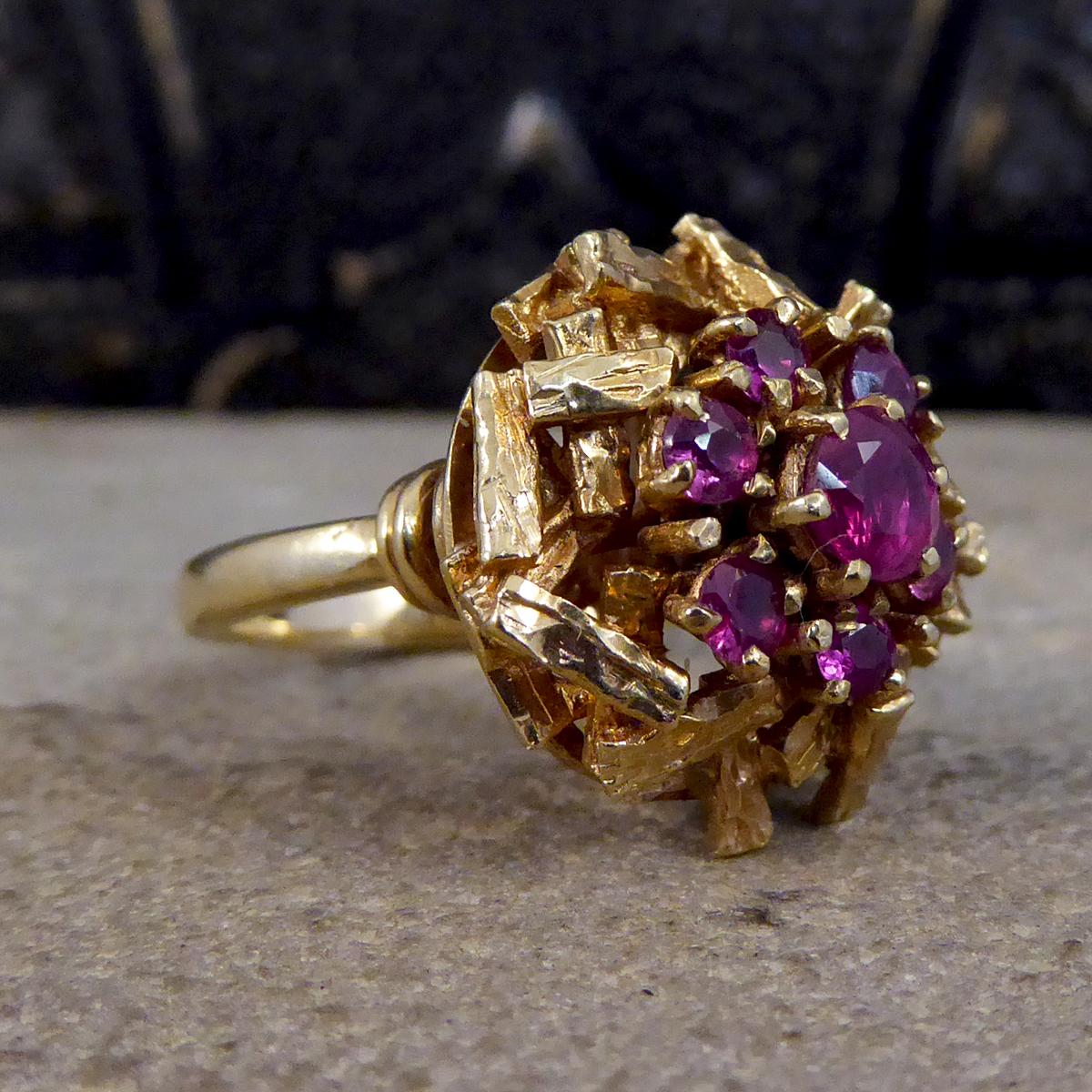 This gorgeous cocktail ring has been hand crafted with a cluster of Rubies. Created from 9ct Yellow Gold and with a Bark Effect on the head of the ring, which reflects the style of that age, this ring has been made in 1968 in London with clear