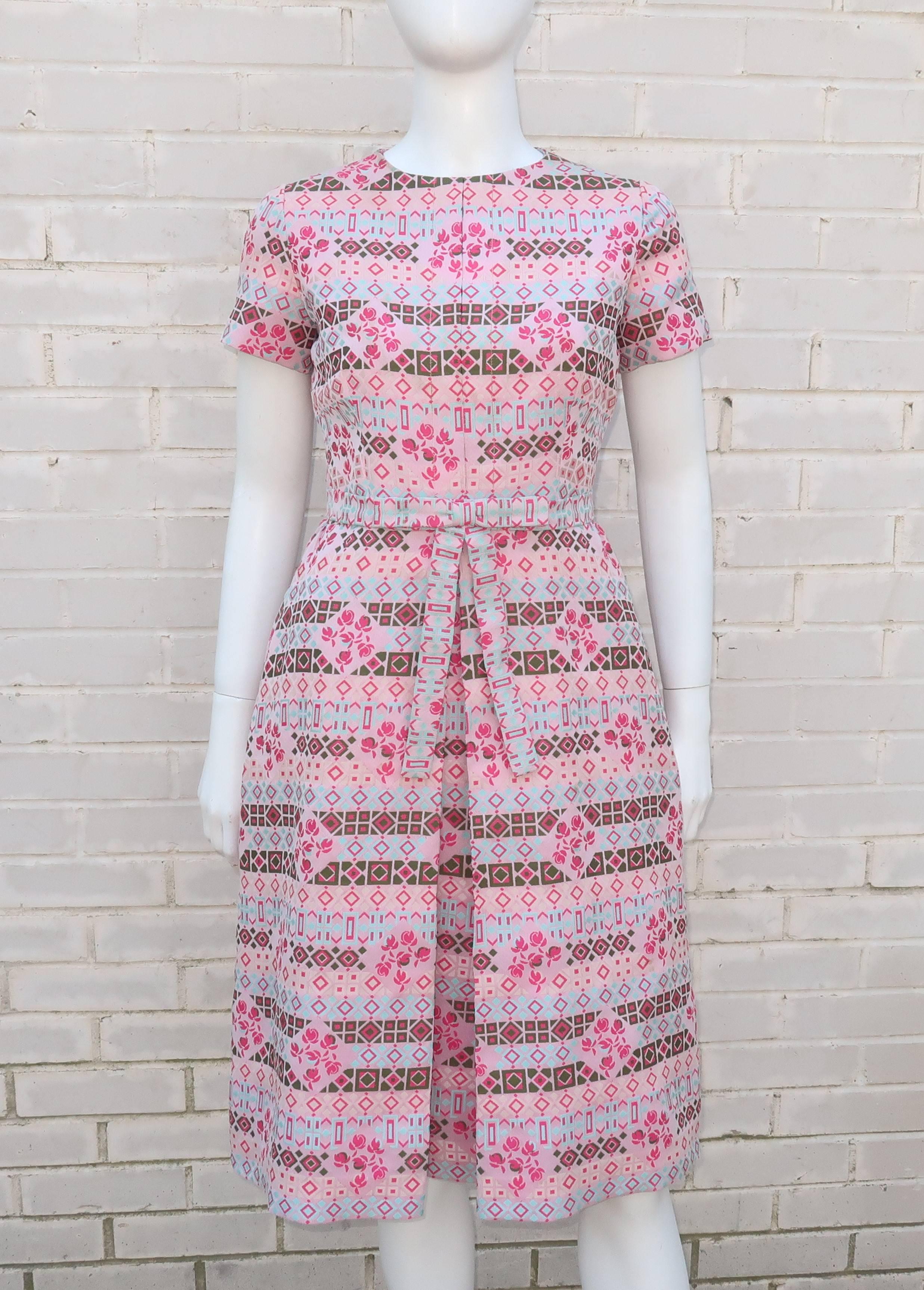 This C.1970 dress from Chester Weinberg is a glorious vision of graphic pink delights.  The geometric design on the brocade style fabric incorporates shades of pink including hot and powder with olive green and pale aqua blue all in a subtle floral