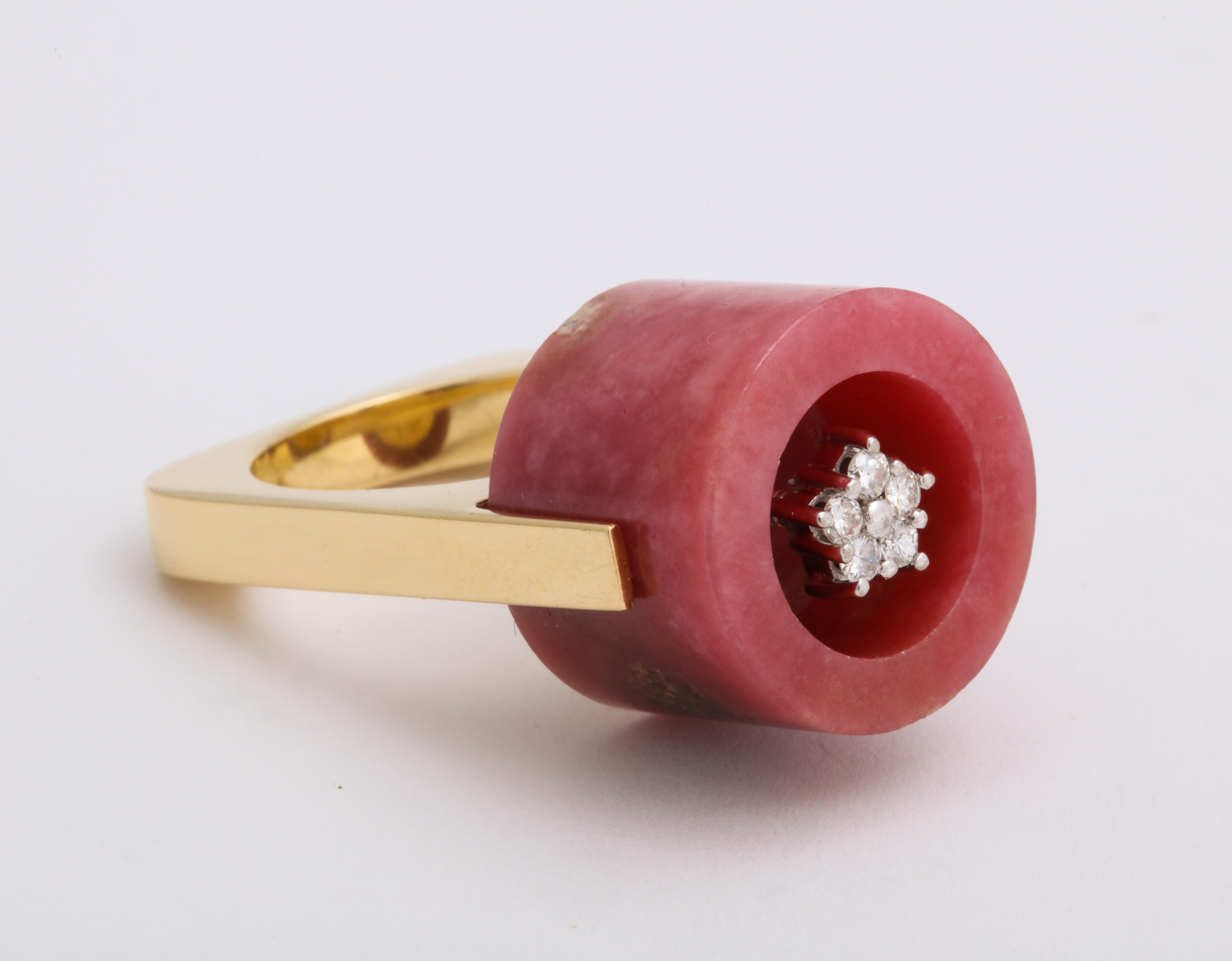 This Rhodonite barrel cut gemstone forms a cave-like home for a tiny cluster of round brilliant diamonds.  The artfully carved gemstone is set into a geometric solid 18K yellow gold ring that looks like it took a few spins on the Studio 54 dance