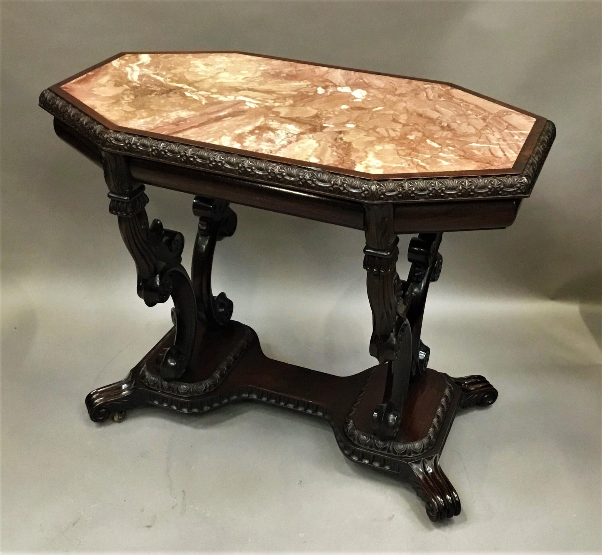 Impressive mid-19th century Anglo-Indian padouk marble top centre table; Ceylonese. The elongated octagonal shaped top, with a finely carved foliate moulded edge, housing the well figured coral colored marble panel. The ogee shaped moulded frieze