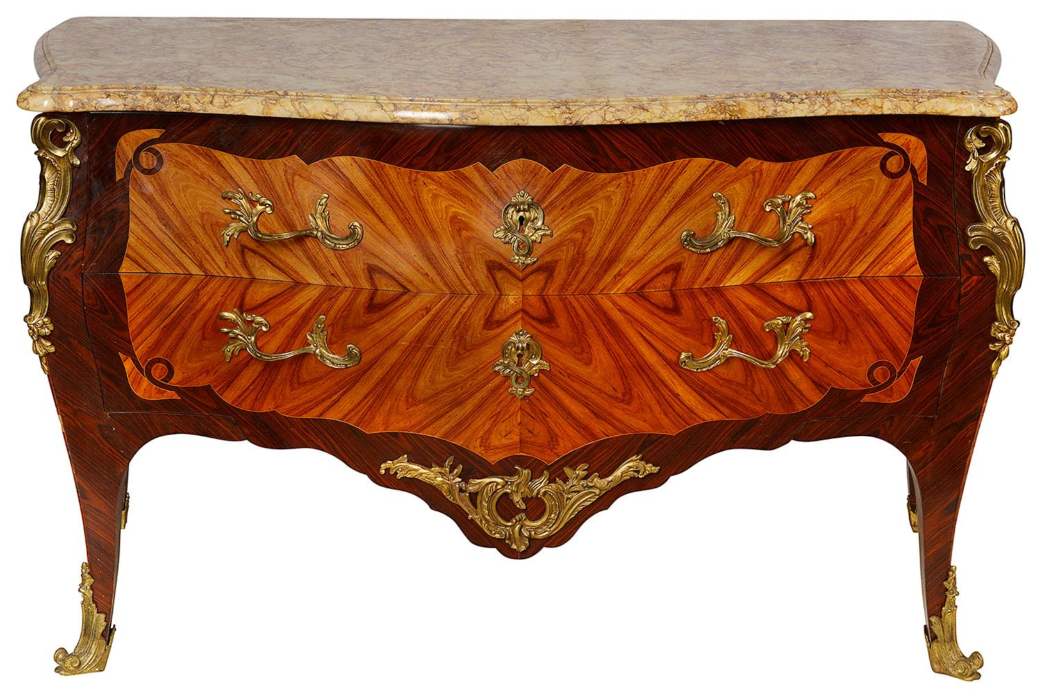 A good quality late 19th century French Louis XVI style Bombe fronted two-drawer commode, having its original marble top, gilded ormolu Rococo influenced mounts and handles, the drawer fronts and sides quarter veneered in tulip wood and raised on