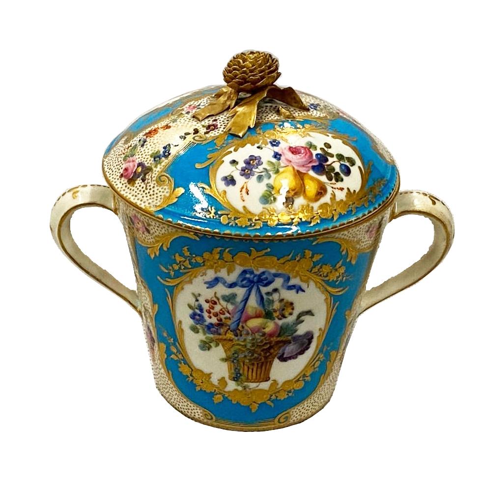 A very good quality late 19th century French 'Sevres' style porcelain lidded chocolate cup and saucer. Having a wonderful gilded flower finial, turquoise ground with scrolling gilded decoration. Floral inset painted panels and classical cherubs.