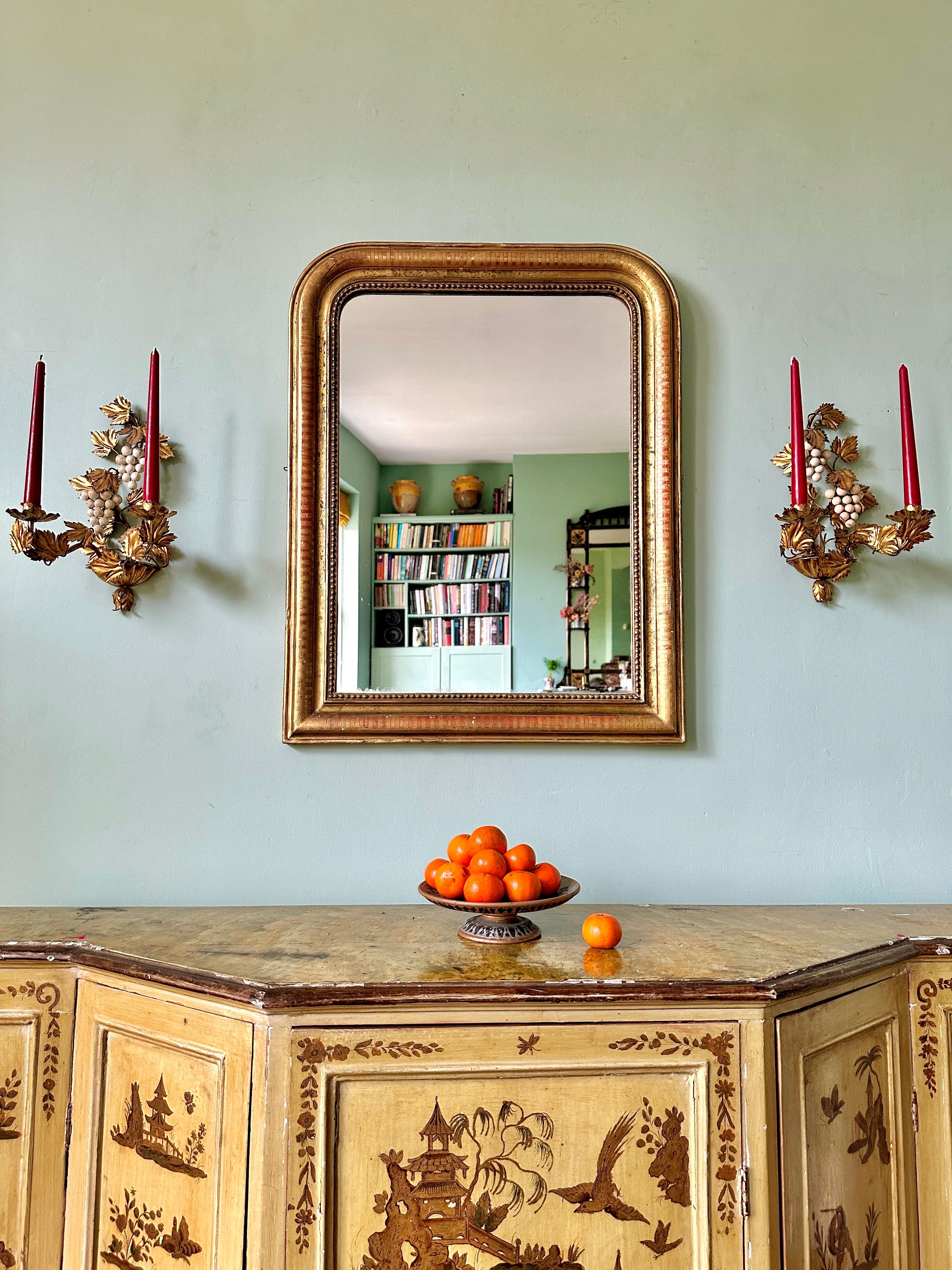 Miroir en arc de cercle Louis Philippe de la fin du 19e siècle.

Magnifique miroir français circa 1840 avec cadre doré géométrique et feuillage gravé. La bordure dorée est superbement décolorée, révélant le manteau de bole rouge qui se trouve en