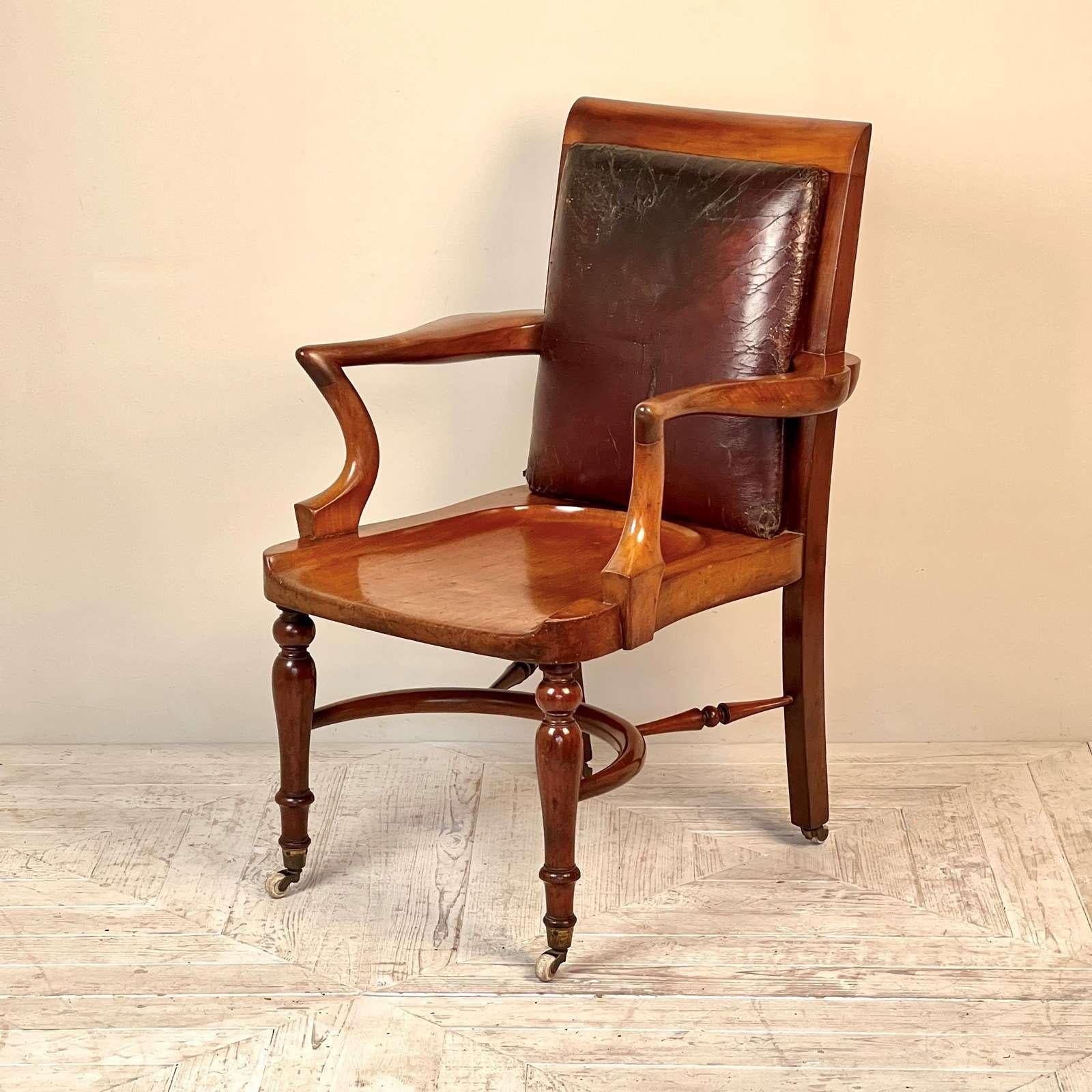 A charming C19th Mahogany Library or Desk Chair by Heals of London from the 1880's. Having a conker brown padded leather back on a solid mahogany frame. The deep cut saddle seat and the nicely formed serpentine arms are particularly nice features.