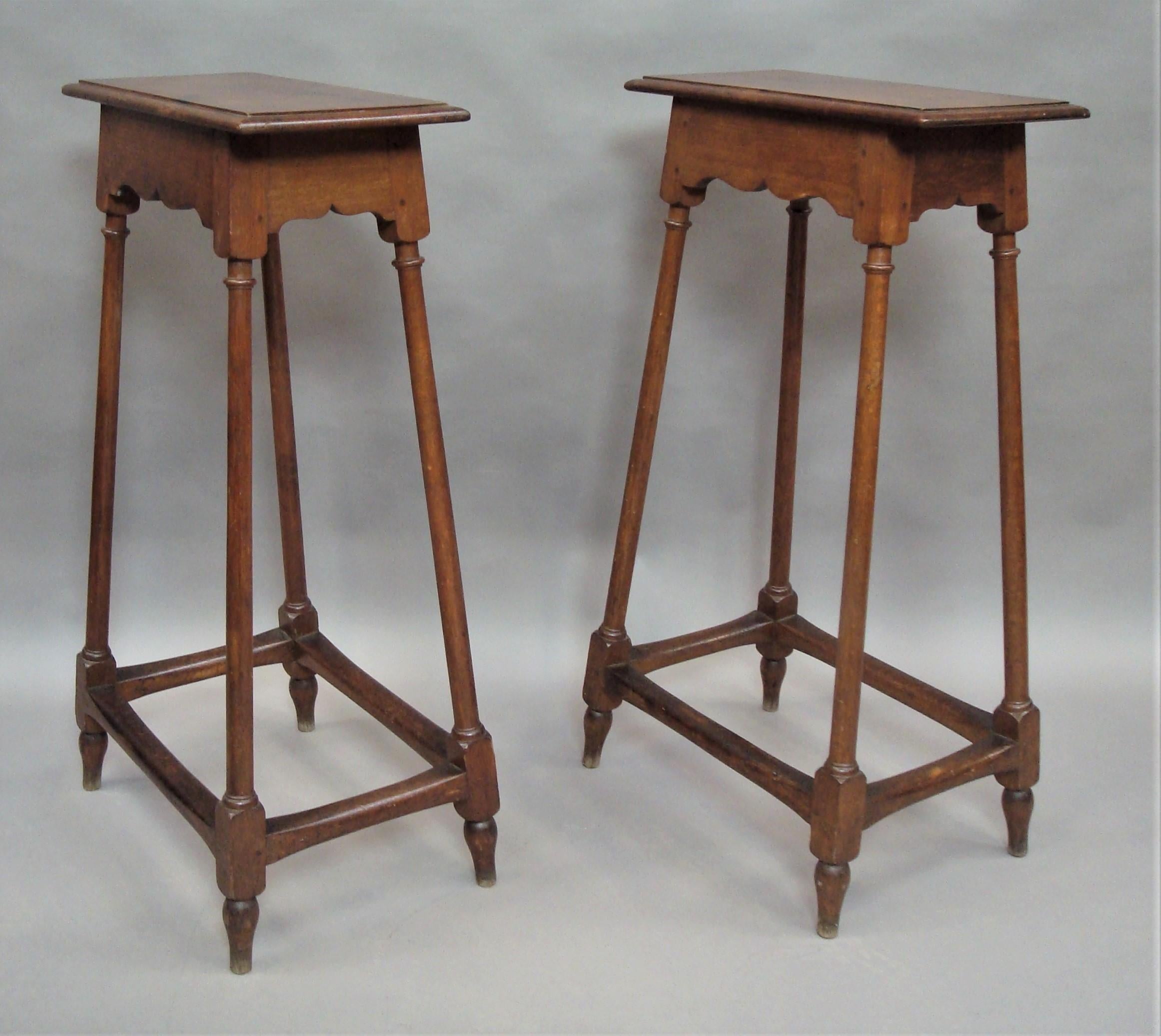 An unusual 19th century pair of oak tables/stands of very tall proportions, tapering design and pegged construction. The rectangular tops with a thumbnail moulded edge above a shaped frieze to all sides raised on slender turned supports united by