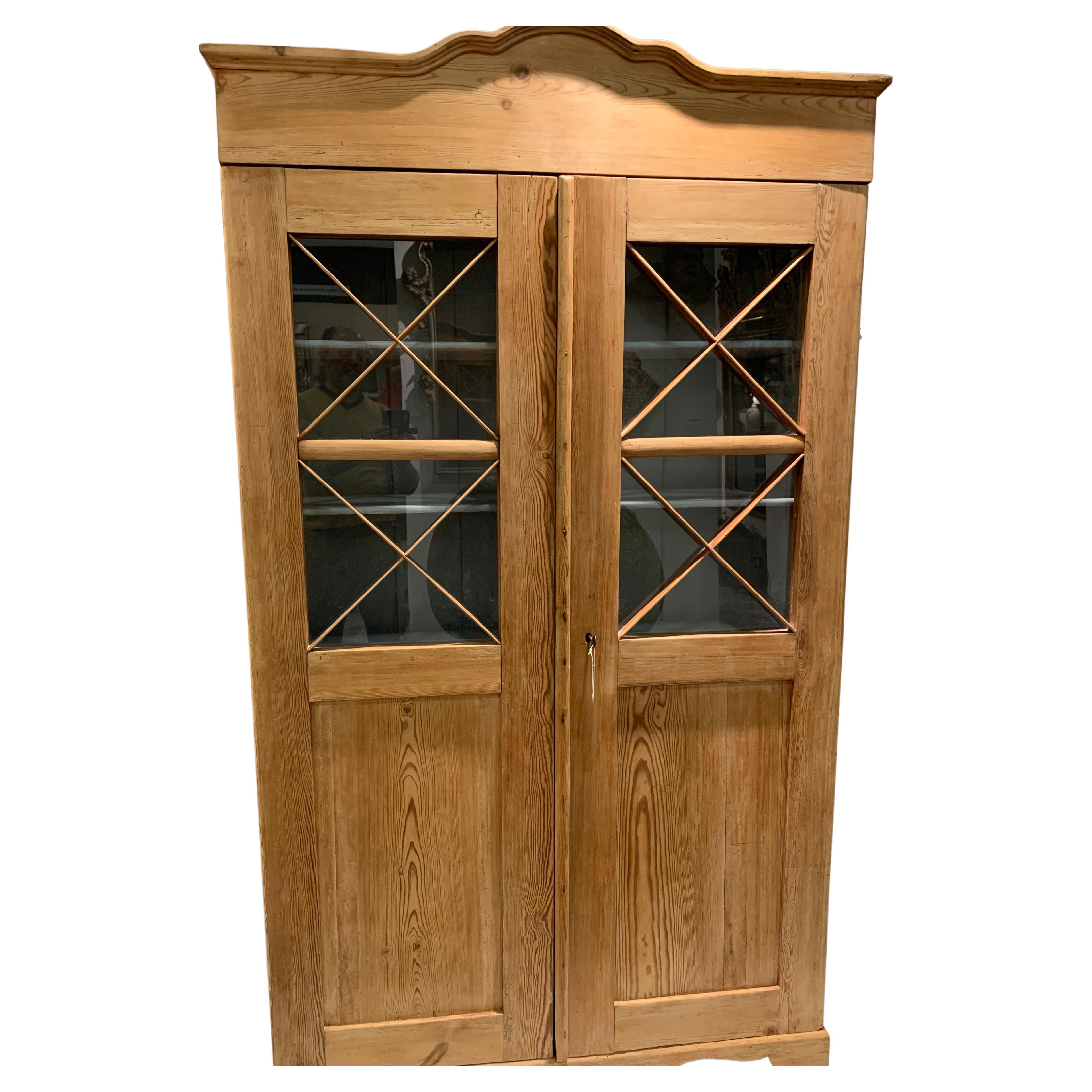 Handsome two door pine cupboard/ cabinet.
This is a lovely understated and useful cabinet which looks great in the flesh.
In one piece, it has a shaped cornice, glazing to the top half of the doors with astragal detail.
The interior has four