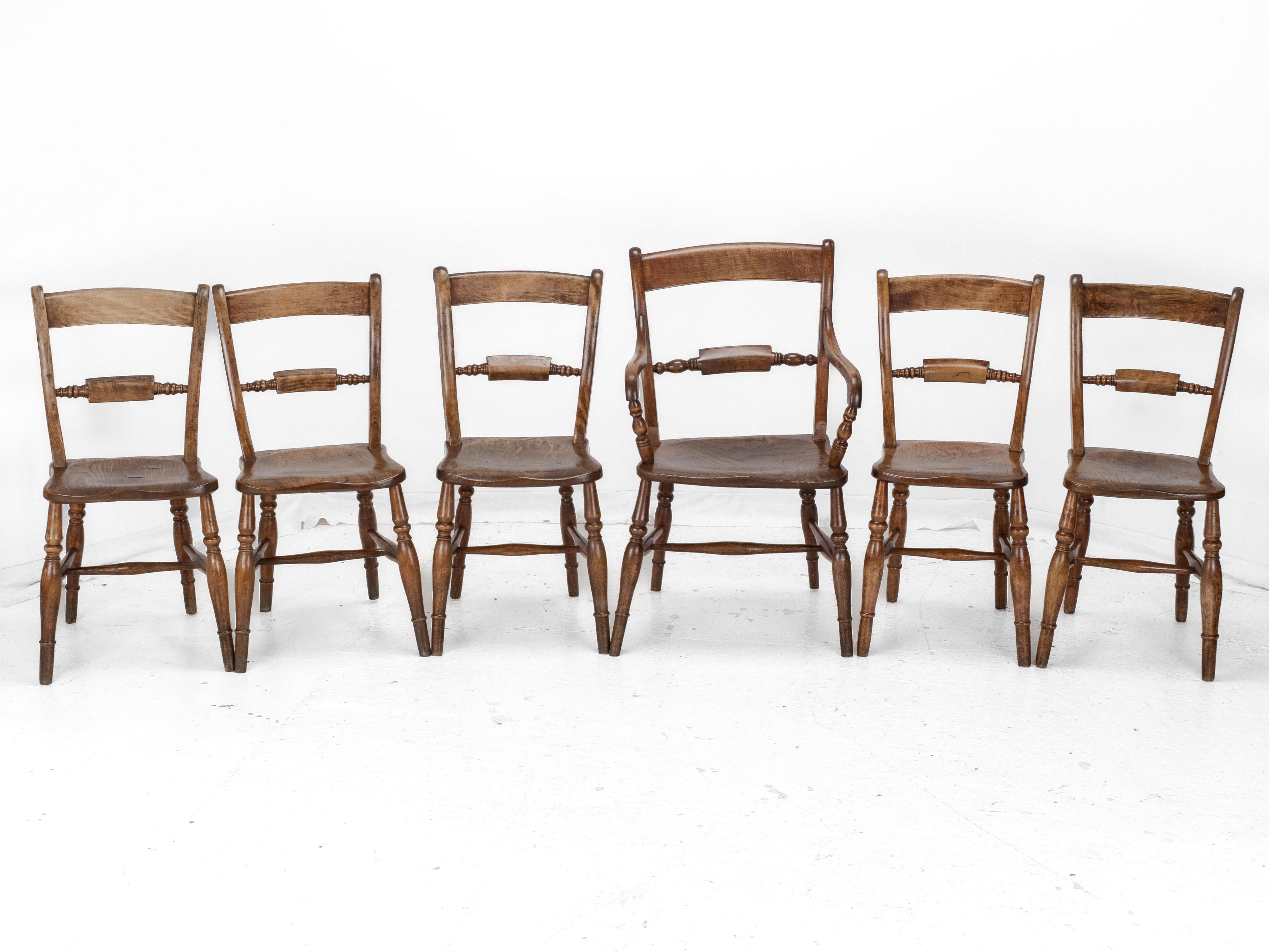 A set of 6 elm, ash and beech country windsor dining chairs and carver, dating from the late 19th century. Comprised of 5 chairs and single carver, this set features attractively figured solid timbers throughout, coupled with quirky natural charm.