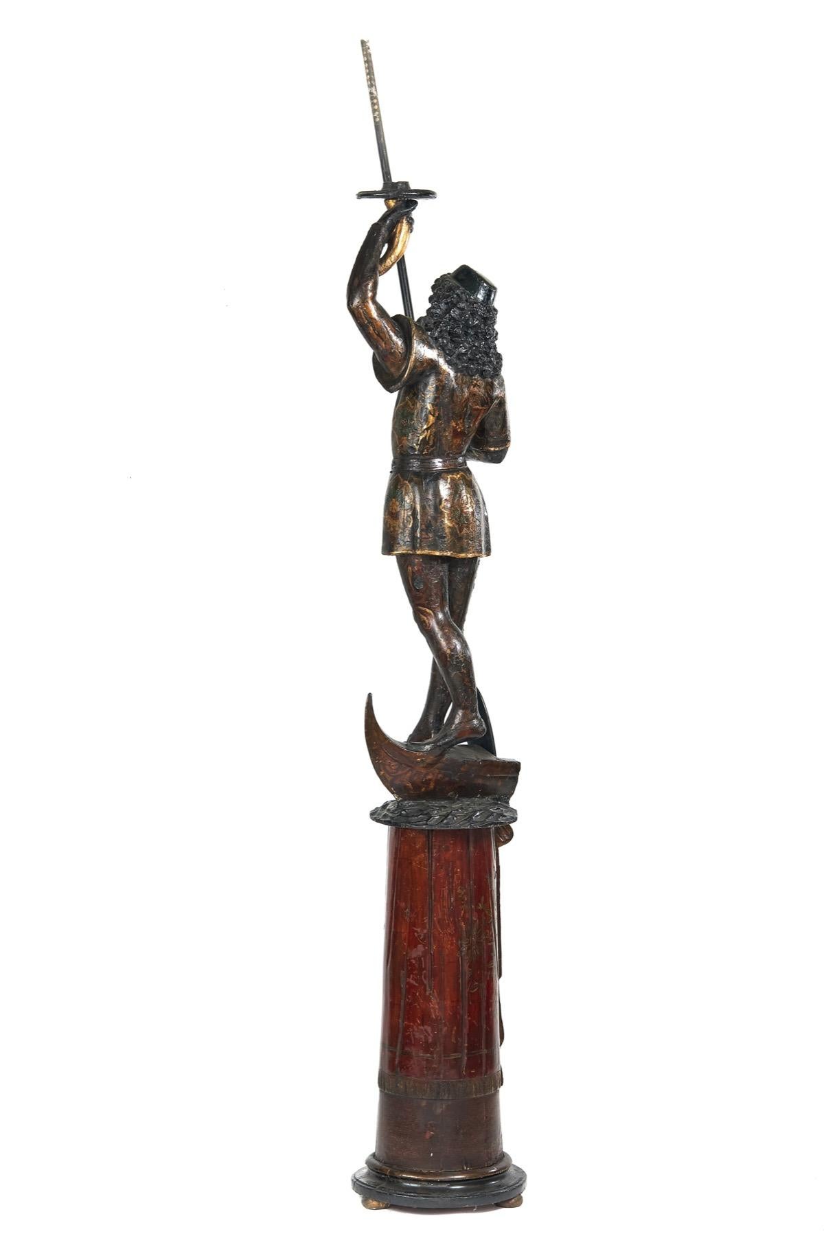 Chandelier vénitien du XIXe siècle à figure de gondolier sculptée,
Décoration polychrome
Gondolier, tenant une pagaie et un porte-bougie en forme de corne d'abondance.
Debout sur une partie de la gondole
La colonne cylindrique conique séparée repose