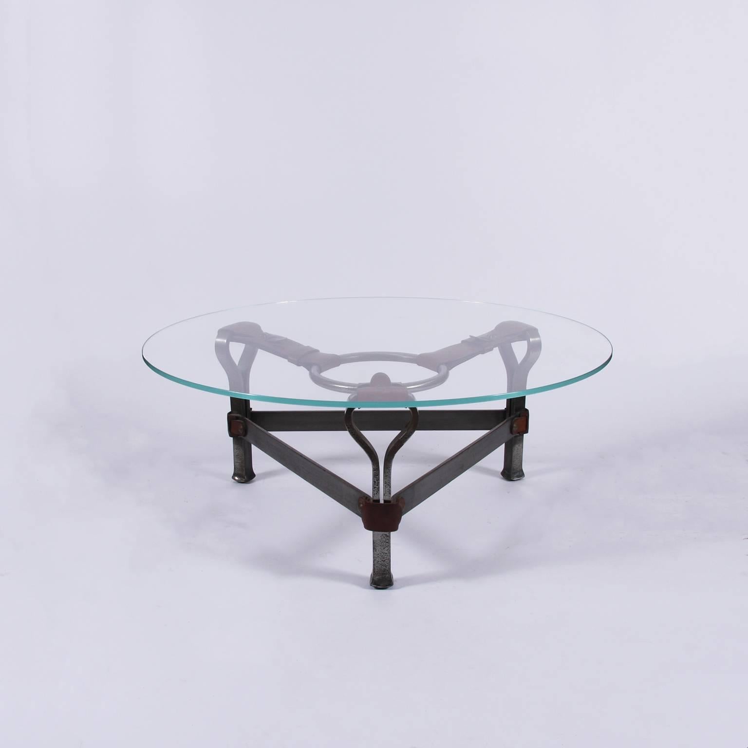 An unusual small coffee table with a wrought iron and leather base with a circular glass top.