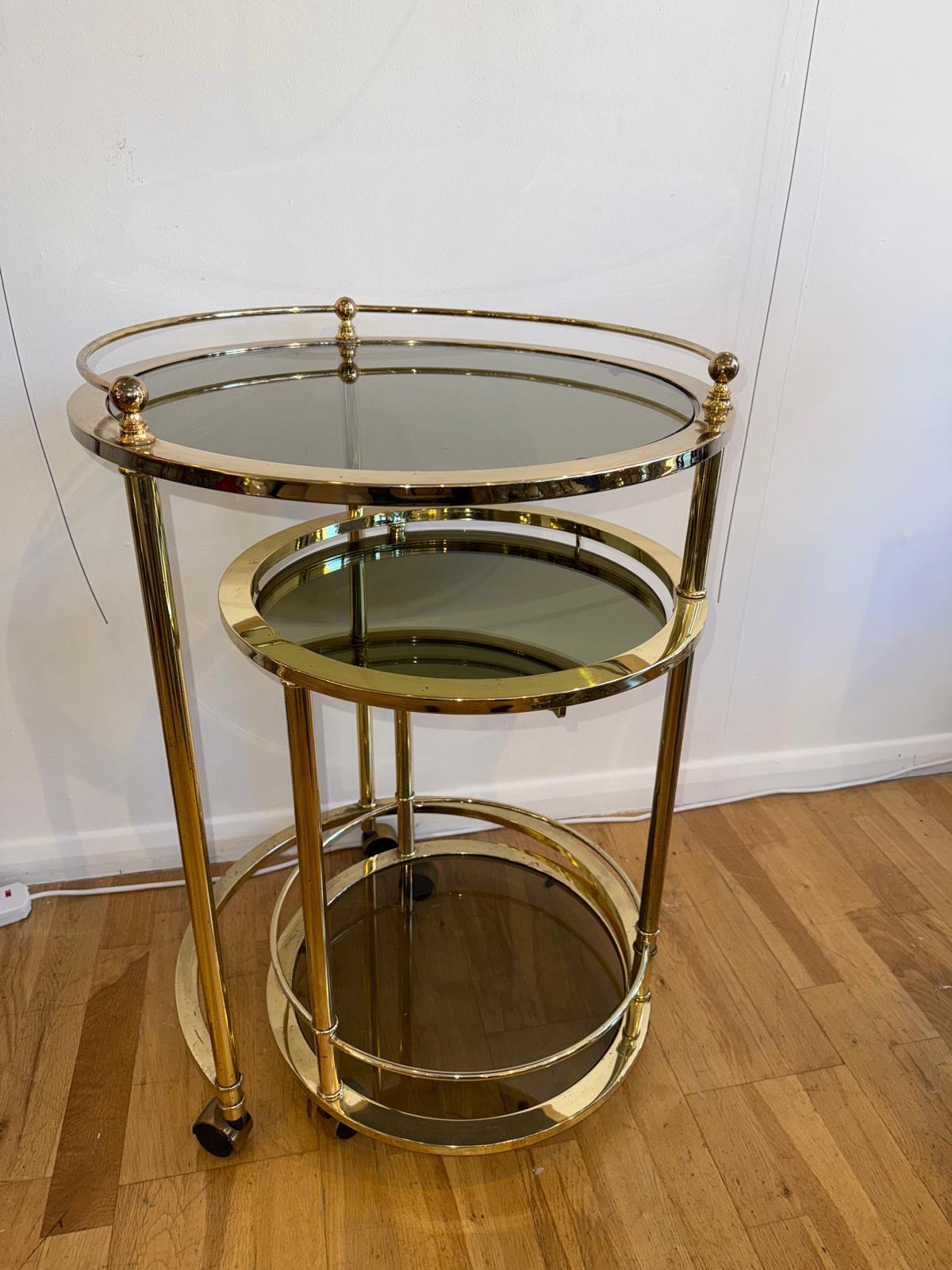 A vintage 3-tier round bar cart in gold done in Milo Baughman style. Tops made of the smoke glass, giving it additional level of chic. Bar cart was made in Italy in 1970s.
Very good vintage condition, with some signs of time and use, visible in the
