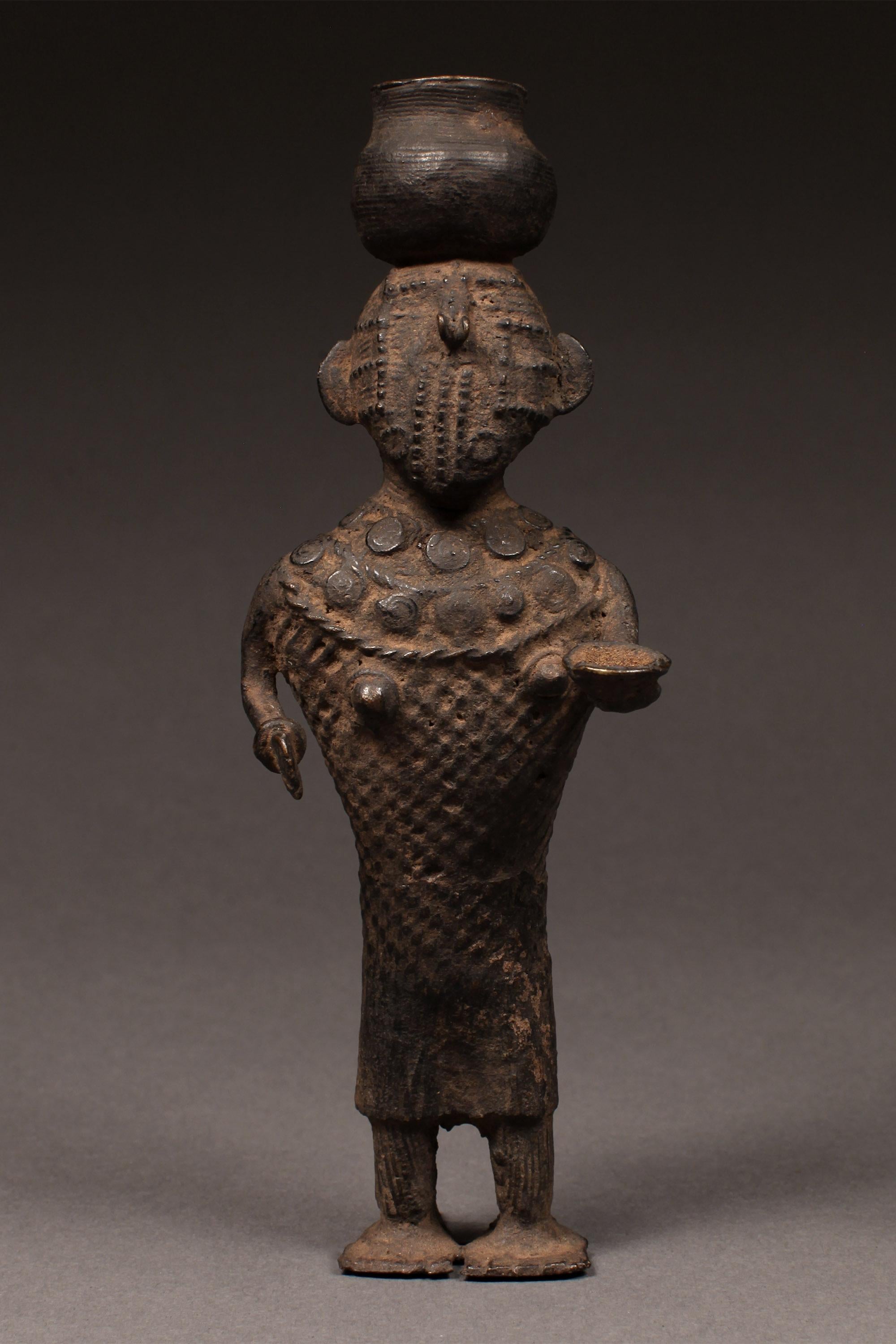 Late 19th century tribal cast bronze standing female figure, Kondh people, Orissa, India

A bridal dowry sculpture in the form of a standing female balancing a pot on her head while holding a dish and a serving utensil. Metal toys such as this were