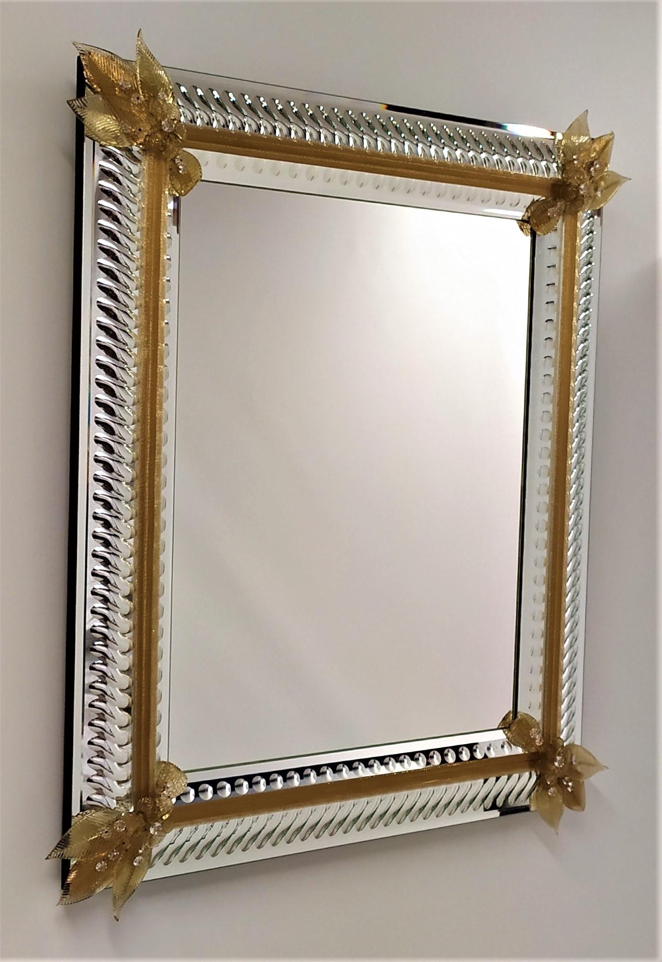 Shimmering rectangular mirror in Murano glass, composed of a frame that embraces the central mirror, carved and polished with stone wheels totally by hand with subjects of waves and bubbles, in the four particular corners in crystal with gold leaf