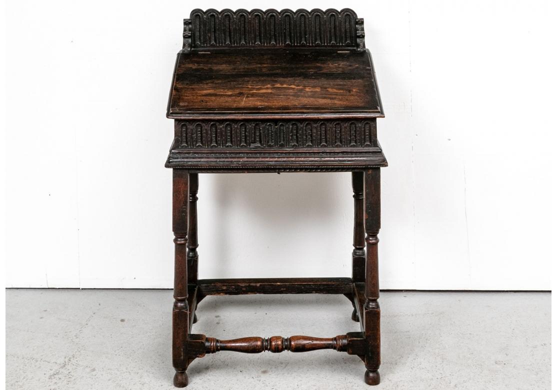 A rare and intricately carved Oak Lectern in original condition. In a very dark black-brown stain. The separately made top with a slant front opening to compartments and with a carved arcade form back splash. The apron on the front and sides with